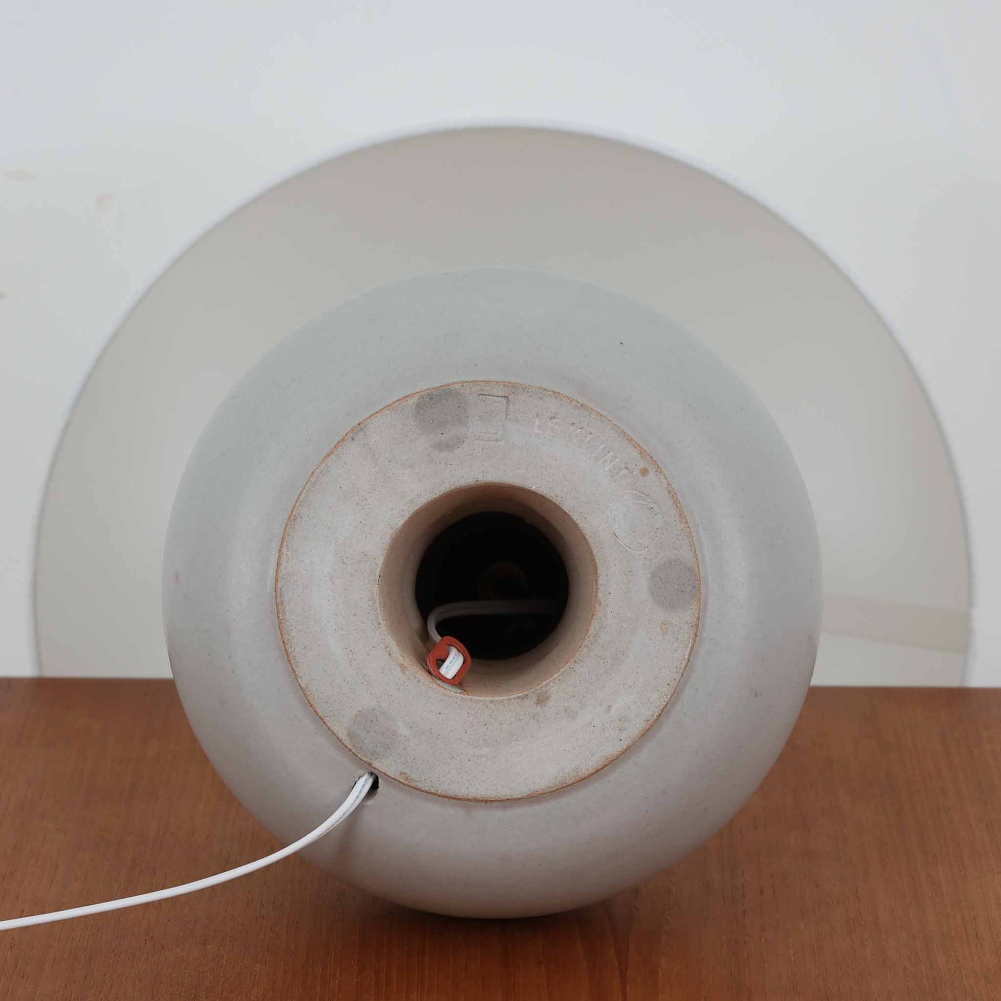 デンマークの照明ブランド Le Klint（レ・クリント）によるテーブルランプで、デザイナーは Ole Boggild（オーレ・ボギル）です。シェードは Le Klint 社製ではありませんが、新品のリネン製プリーツシェードを合わせており、全体として上品で柔らかな印象に仕上がっています。丸みを帯びた陶磁器ベースに、すらりと伸びるネックの造形が美しく、北欧デザインらしい穏やかな佇まいを感じさせます。ややグレーがかったマットな質感が上品で、リネンシェードを通した柔らかな光が空間を優しく包み込みます。シンプルながら存在感があり、リビングやベッドサイドなどさまざまなシーンでお使いいただけます。北欧の上質な灯りをお楽しみいただけるビンテージランプです。