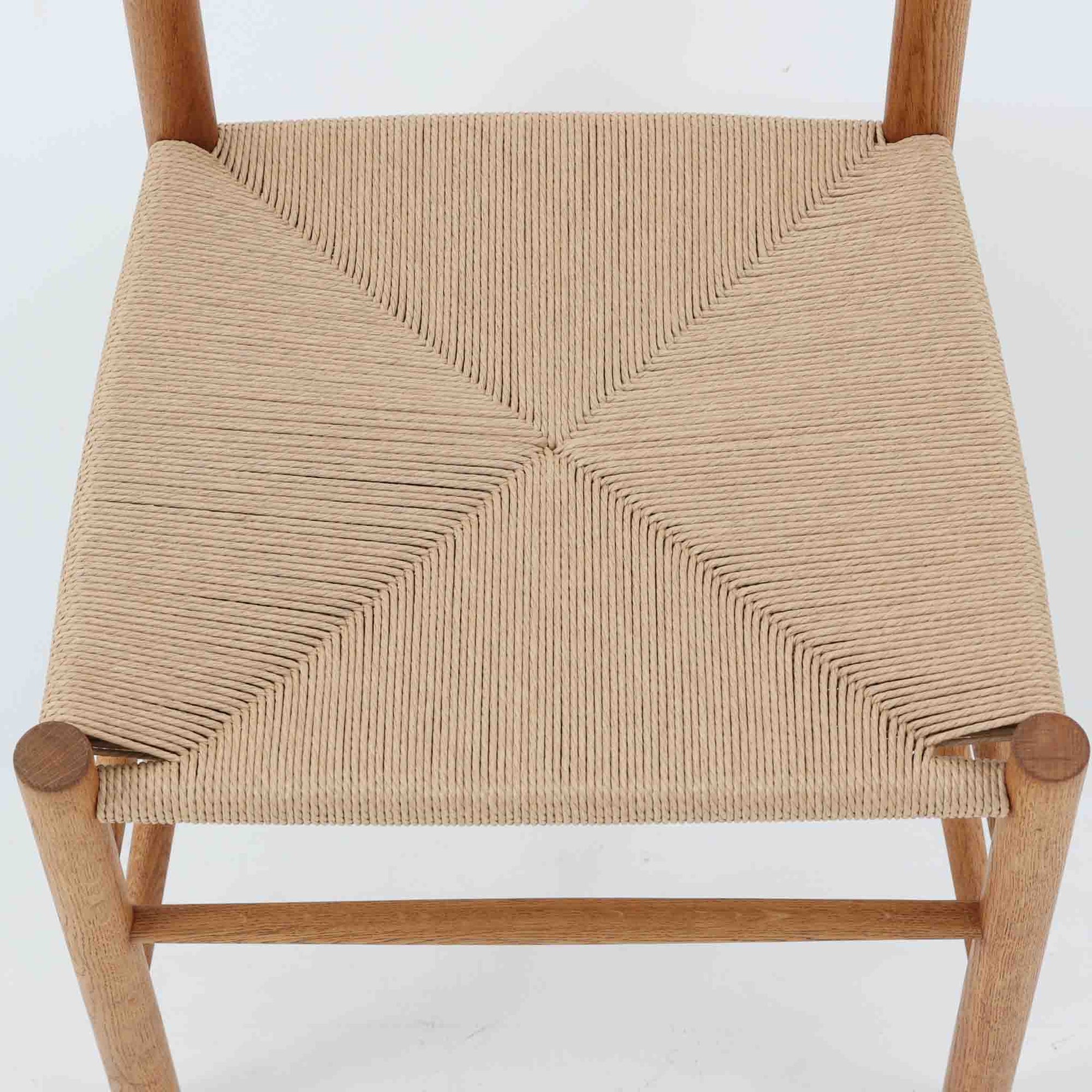 デンマークを代表するデザイナー、Borge MogensenによってFDBのためにデザインされたJ39チェアは、オーク材の丸脚と座面に丁寧に編み込まれたペーパーコードが特徴の、素朴ながらも完成度の高い北欧ビンテージチェアです。農村のキッチンチェアをルーツに持つそのデザインは、無駄を省いた潔い構造と機能美が融合し、空間に凛とした佇まいをもたらします。ダイニングはもちろん、ワークチェアやアクセントチェアとしても重宝する一脚です。