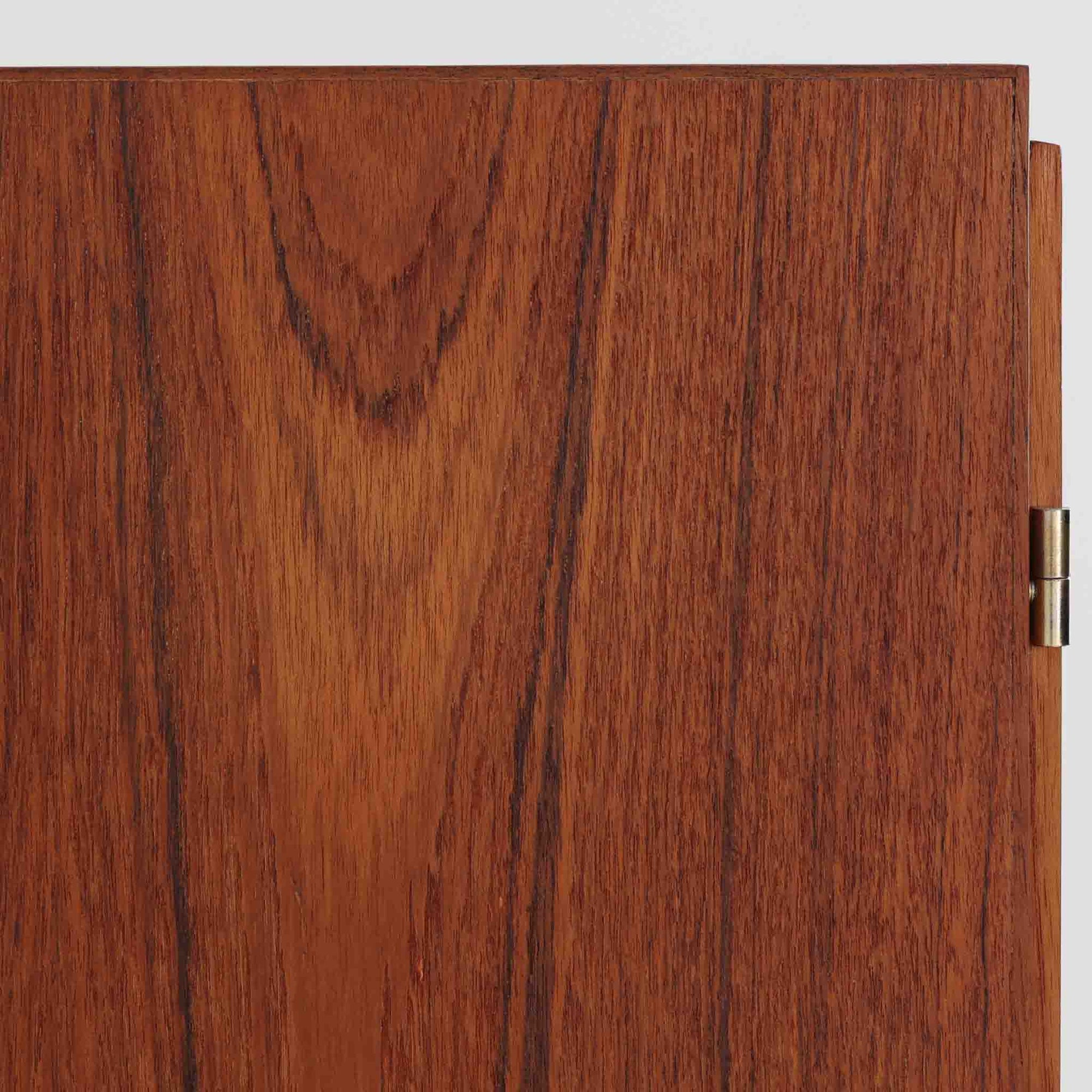 デンマーク製の収納キャビネットです。上段には観音開きの扉内に可動棚が設けられており、食器や書類をすっきりと整理できます。内部まで丁寧に仕上げられており、扉を開けてお気に入りの器やオブジェを飾る“見せる収納”としても楽しめます。扉には鍵が付属しており、大切なものを安全に保管することも可能です。下段には2杯の引き出しが備わり、小物類や日用品の収納にも便利。チーク材の豊かな木目と深みのある色合いが美しく、北欧家具らしい温もりを感じさせます。脚部のテーパー形状が全体を軽やかに見せ、シンプルながら上質な存在感を放つ一台です。