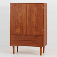 デンマーク製の収納キャビネットです。上段には観音開きの扉内に可動棚が設けられており、食器や書類をすっきりと整理できます。内部まで丁寧に仕上げられており、扉を開けてお気に入りの器やオブジェを飾る“見せる収納”としても楽しめます。扉には鍵が付属しており、大切なものを安全に保管することも可能です。下段には2杯の引き出しが備わり、小物類や日用品の収納にも便利。チーク材の豊かな木目と深みのある色合いが美しく、北欧家具らしい温もりを感じさせます。脚部のテーパー形状が全体を軽やかに見せ、シンプルながら上質な存在感を放つ一台です。