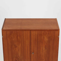 デンマーク製の収納キャビネットです。上段には観音開きの扉内に可動棚が設けられており、食器や書類をすっきりと整理できます。内部まで丁寧に仕上げられており、扉を開けてお気に入りの器やオブジェを飾る“見せる収納”としても楽しめます。扉には鍵が付属しており、大切なものを安全に保管することも可能です。下段には2杯の引き出しが備わり、小物類や日用品の収納にも便利。チーク材の豊かな木目と深みのある色合いが美しく、北欧家具らしい温もりを感じさせます。脚部のテーパー形状が全体を軽やかに見せ、シンプルながら上質な存在感を放つ一台です。