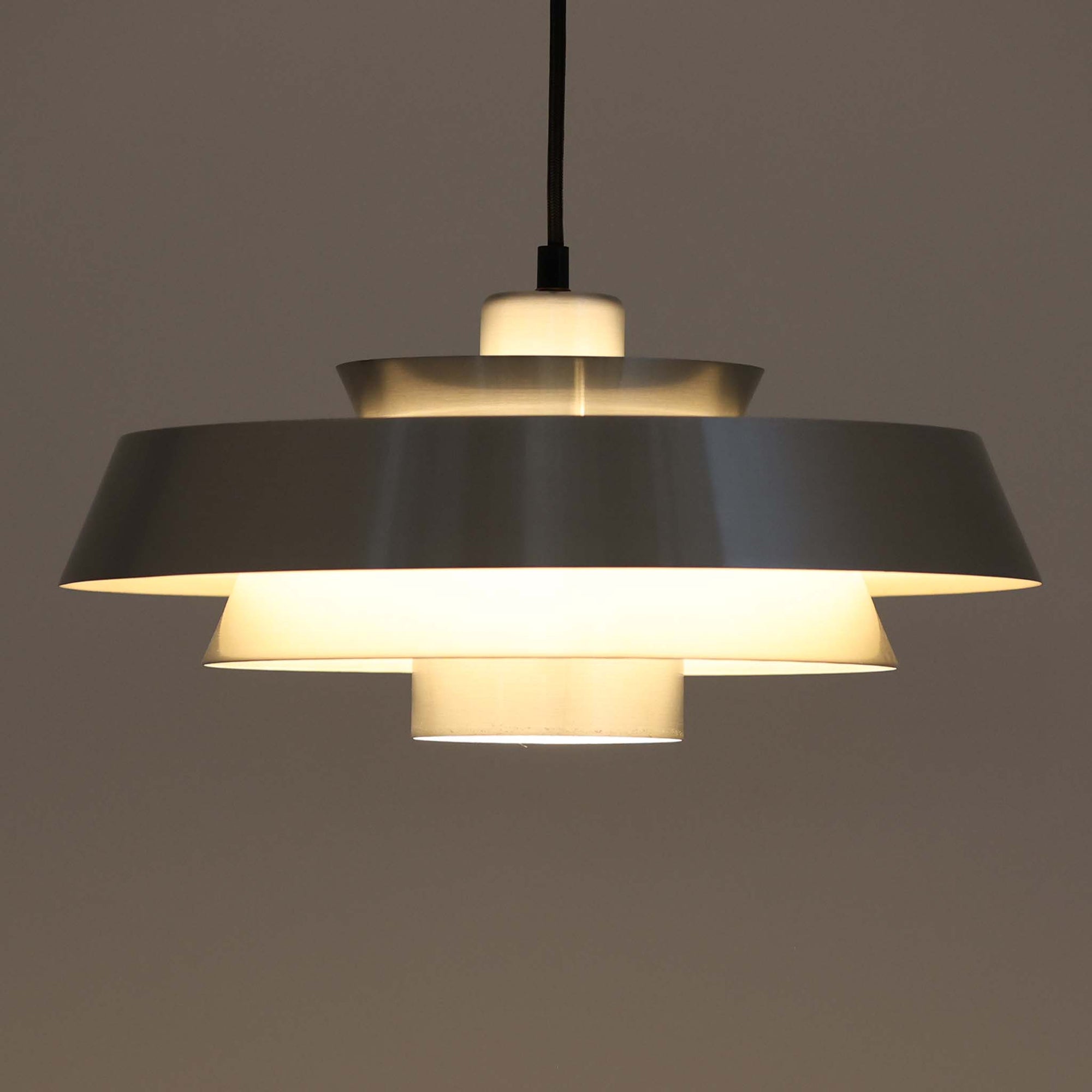 Jo Hammerborgがデザインし、Fog & Morup社から発表されたペンダントライト「Nova」です。アルミを用いた精緻なシェード構造が特徴で、直径40cmのサイズはダイニングやリビングの照明に適しています。重なり合うシェードが光を柔らかく拡散し、眩しさを抑えながら温かみのある空間を演出。シルバーの質感と洗練されたフォルムは、モダンでありながら北欧デザインらしい静かな存在感を放ちます。ビンテージならではの希少性に加え、素材の経年変化が加わることで、光とともに独特の風合いを楽しめる逸品です。