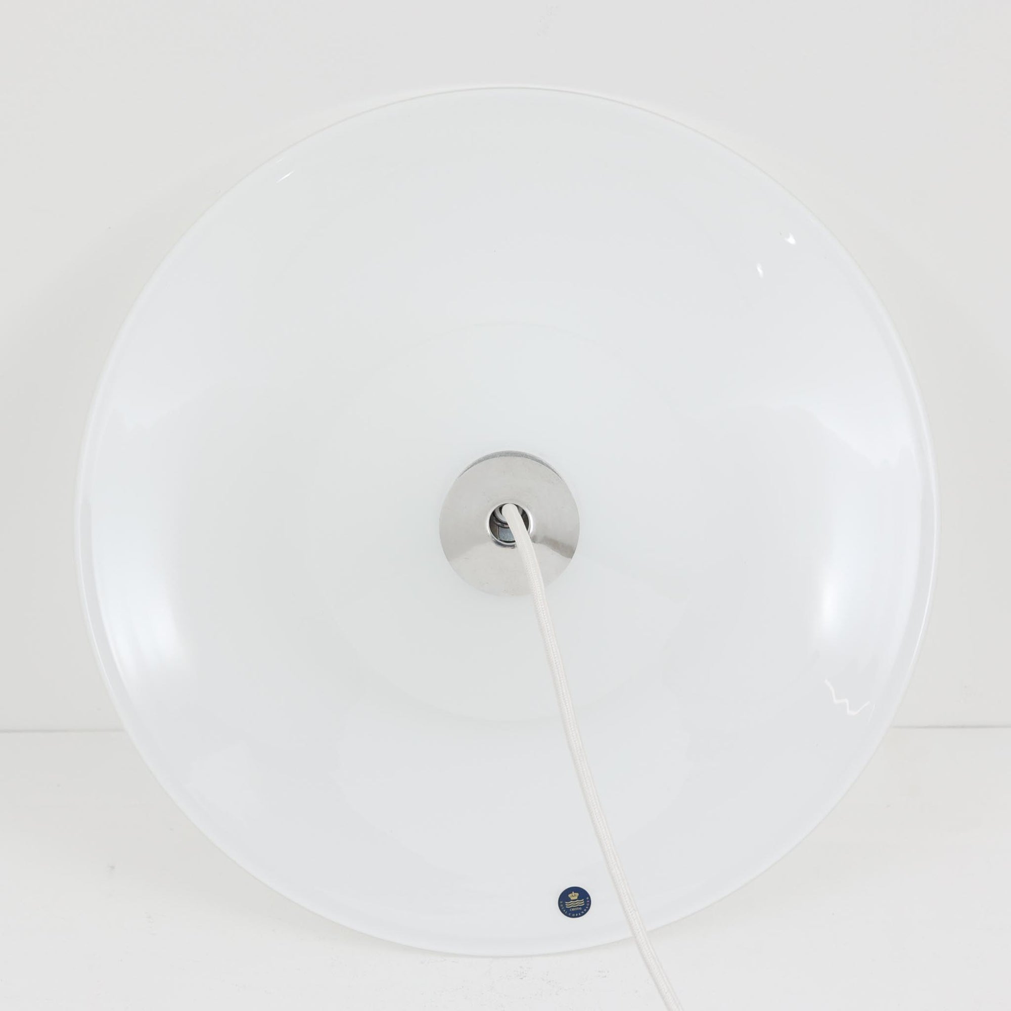 Torben Jorgensenによってデザインされ、Royal Copenhagen社から発表されたペンダントライト「Opus」です。直径42cmの大ぶりなサイズで、ガラスとアルミの組み合わせによる透明感と光沢感が際立ちます。上部のすりガラス部分から柔らかく光が広がり、下部のシェードが直接光を和らげて空間全体を心地よく照らします。シンプルでありながら優美なフォルムは、ダイニングやリビングに上質なアクセントを添え、北欧ビンテージならではのモダンで落ち着いた雰囲気を演出します。希少な一灯です。