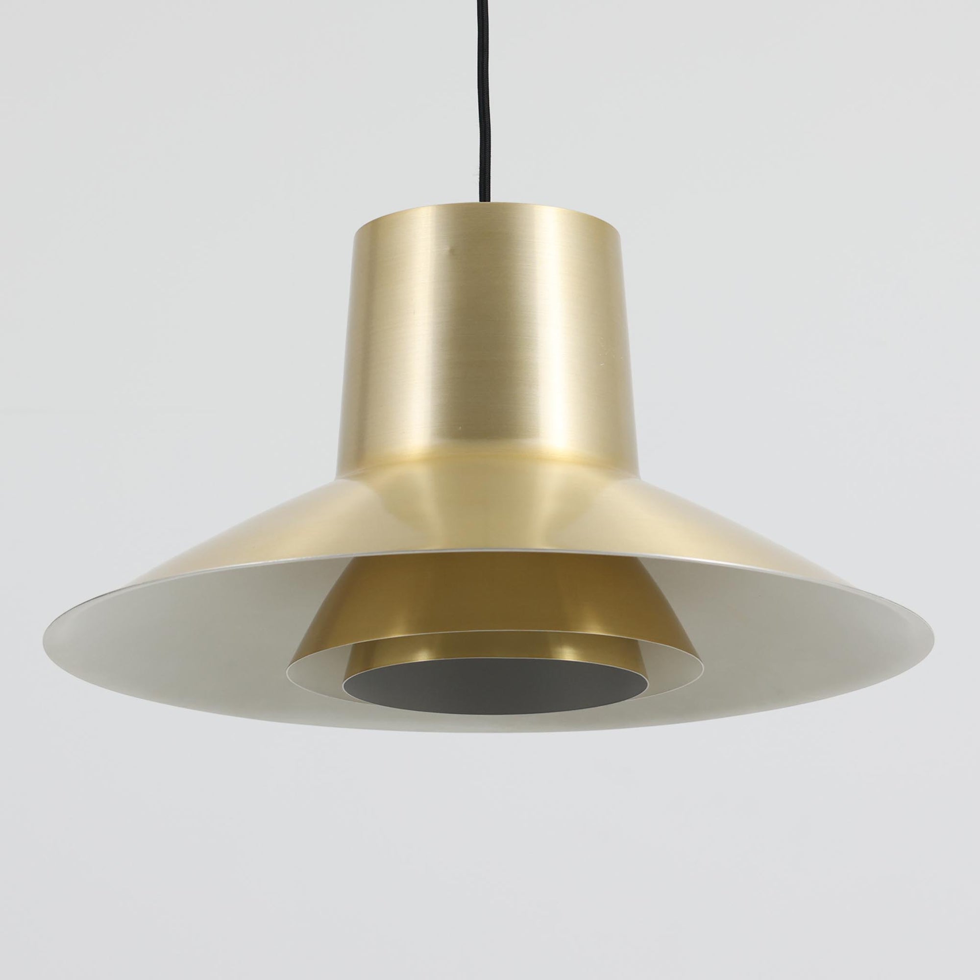 Svend Middelboeがデザインし、Nordisk Solar社より発表されたペンダントライト「Auditorie」です。直径49cmの大ぶりなサイズと、アルミ素材に施された美しい真鍮色の仕上げが特徴で、点灯時には下方向に効率よく光を届けつつ、柔らかく反射する光が空間を上品に彩ります。大胆なフォルムながらもバランスの取れたデザインは、1960年代北欧モダンのエッセンスを凝縮しており、ダイニングやリビングの主照明として存在感を放ちます。経年により深みを増した表情はビンテージならではの魅力で、機能性と美しさを兼ね備えた希少な一灯です。