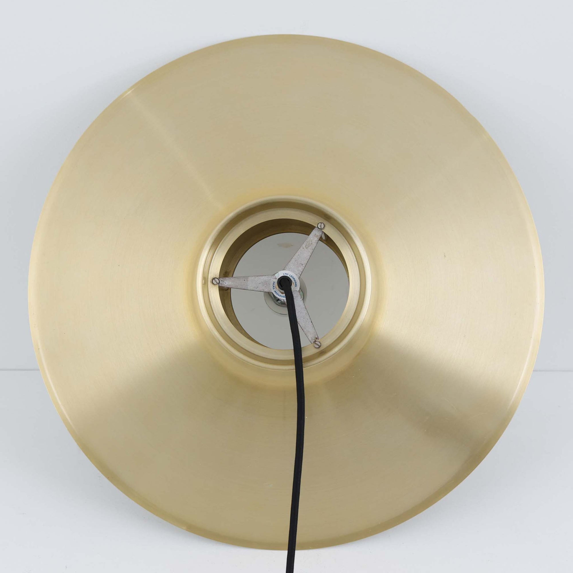 Svend Middelboeがデザインし、Nordisk Solar社より発表されたペンダントライト「Auditorie」です。直径49cmの大ぶりなサイズと、アルミ素材に施された美しい真鍮色の仕上げが特徴で、点灯時には下方向に効率よく光を届けつつ、柔らかく反射する光が空間を上品に彩ります。大胆なフォルムながらもバランスの取れたデザインは、1960年代北欧モダンのエッセンスを凝縮しており、ダイニングやリビングの主照明として存在感を放ちます。経年により深みを増した表情はビンテージならではの魅力で、機能性と美しさを兼ね備えた希少な一灯です。