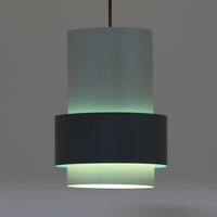 Jo HammerborgがFog & Morup社のためにデザインした「Central」ペンダントライトです。直径23cmのコンパクトなサイズながら、スチール製の二重シリンダー構造が特徴的で、点灯時には上下から光が広がり独特の陰影を演出します。外側のグレーと内側のホワイトがコントラストを生み、点灯時にはほのかなグリーンの光が漏れ出す美しいデザインです。ダイニングや小スペースに適したサイズで、北欧モダンのエッセンスを感じさせるビンテージ照明です。シェードの内側に施されたグリーンの塗装が、点灯時に柔らかなニュアンスを加え、空間に独特の雰囲気を演出します。