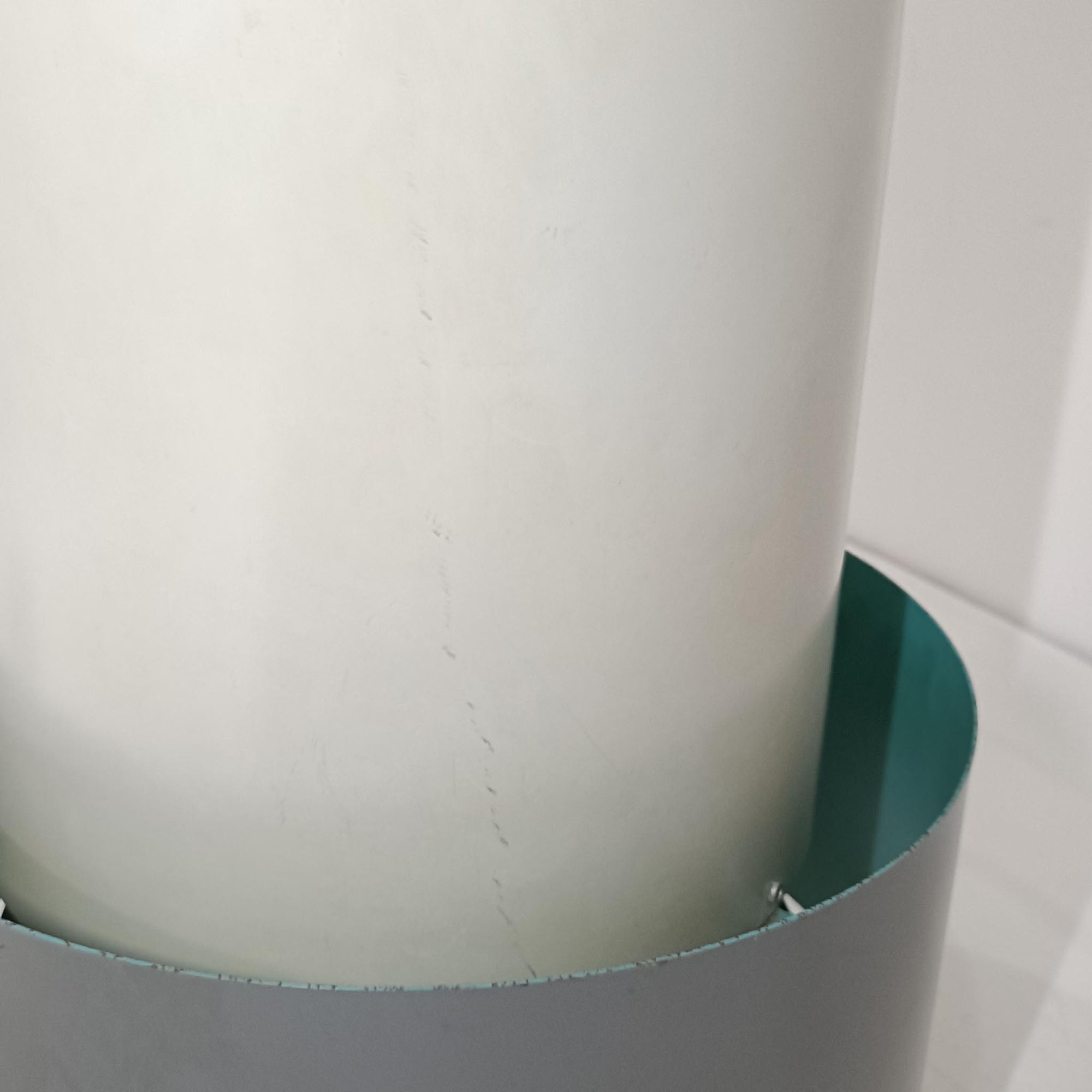 Jo HammerborgがFog &amp; Morup社のためにデザインした「Central」ペンダントライトです。直径23cmのコンパクトなサイズながら、スチール製の二重シリンダー構造が特徴的で、点灯時には上下から光が広がり独特の陰影を演出します。外側のグレーと内側のホワイトがコントラストを生み、点灯時にはほのかなグリーンの光が漏れ出す美しいデザインです。ダイニングや小スペースに適したサイズで、北欧モダンのエッセンスを感じさせるビンテージ照明です。シェードの内側に施されたグリーンの塗装が、点灯時に柔らかなニュアンスを加え、空間に独特の雰囲気を演出します。