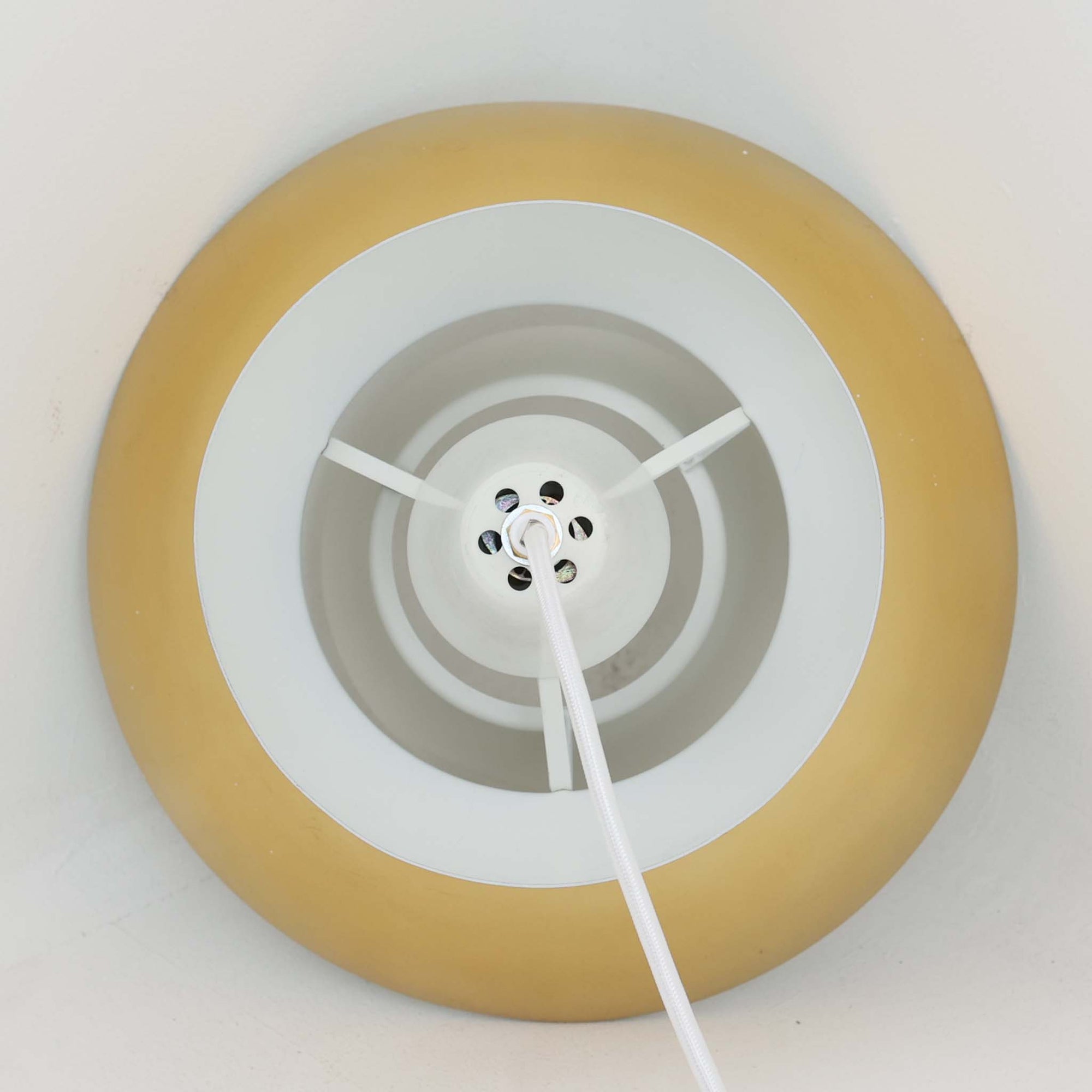 Louis Poulsen社製の小ぶりなペンダントライト「Doo-Wop」です。直径29cmの扱いやすいサイズで、真鍮カラーの上部シェードとホワイトの内側シェードのコントラストが美しいデザイン。点灯時には上下に光を広げ、空間を柔らかく照らし出します。1950年代にデンマーク海軍と共同で開発されたモデルで、シンプルながらも存在感のある佇まいが魅力です。ダイニングやキッチンに適しており、ビンテージならではの味わい深い風合いをお楽しみいただけます。さらに、現行品とは異なりシェードはマイナスネジで固定されており、当時のオリジナルならではのディテールが残されています。