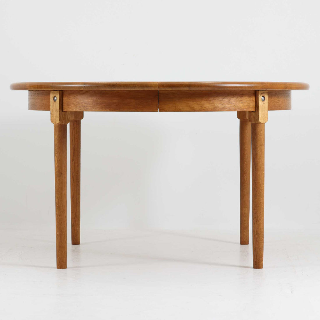 デンマーク製の円形エクステンションダイニングテーブルです。天板には贅沢にオーク無垢材が使用され、木の温もりとしっかりとした造りが魅力。拡張板にはオーク突板が用いられており、ラウンド形状からオーバル形状へと変化する機能的な構造が特徴です。経年により深みを増した木肌が味わい深く、北欧ビンテージならではの温かみのある雰囲気を演出します。普段の食卓としてはもちろん、来客時にも活躍する実用性と美しさを兼ね備えた一台です。