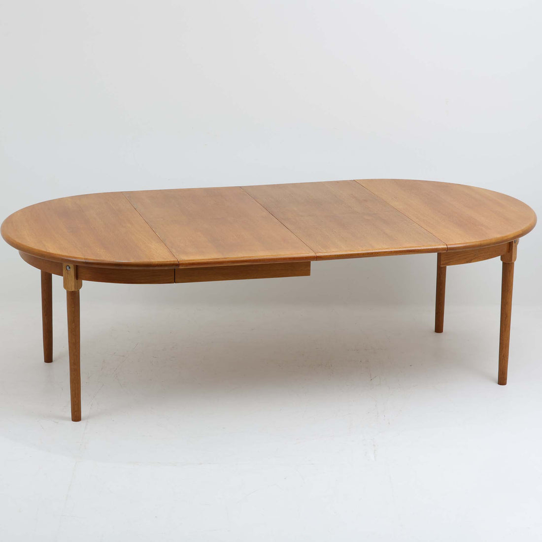 デンマーク製の円形エクステンションダイニングテーブルです。天板には贅沢にオーク無垢材が使用され、木の温もりとしっかりとした造りが魅力。拡張板にはオーク突板が用いられており、ラウンド形状からオーバル形状へと変化する機能的な構造が特徴です。経年により深みを増した木肌が味わい深く、北欧ビンテージならではの温かみのある雰囲気を演出します。普段の食卓としてはもちろん、来客時にも活躍する実用性と美しさを兼ね備えた一台です。