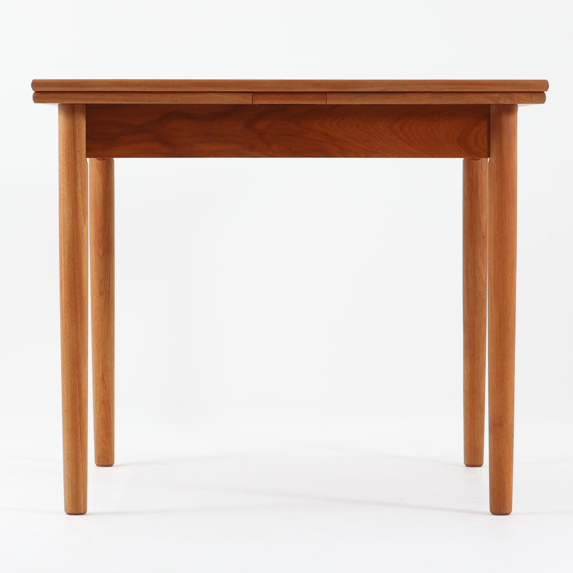 素材と構造の完成度の高さが際立つ正方形エクステンションダイニングテーブルです。天板には上質なチーク材が用いられ、木目の美しさと経年変化による深みのある色合いが北欧ビンテージらしい佇まいを演出します。普段はコンパクトな正方形として使用でき、来客時には左右の天板を引き出すことで広々としたサイズへと拡張可能な実用的な構造です。細身の脚部と幕板のバランスも良く、空間に軽やかな印象を与えます。