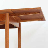 素材と構造の完成度の高さが際立つ正方形エクステンションダイニングテーブルです。天板には上質なチーク材が用いられ、木目の美しさと経年変化による深みのある色合いが北欧ビンテージらしい佇まいを演出します。普段はコンパクトな正方形として使用でき、来客時には左右の天板を引き出すことで広々としたサイズへと拡張可能な実用的な構造です。細身の脚部と幕板のバランスも良く、空間に軽やかな印象を与えます。