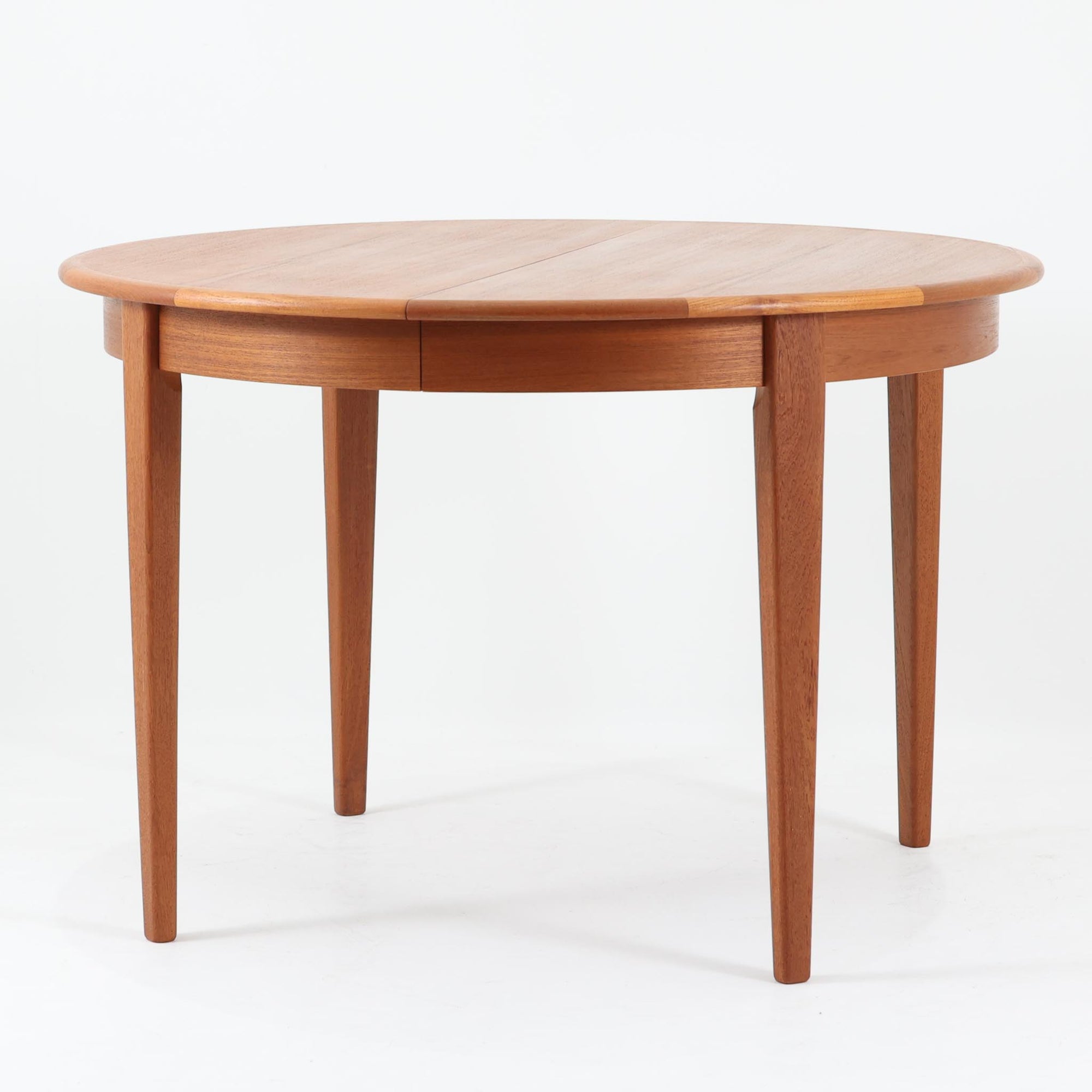 デンマーク製の北欧ビンテージ円形ダイニングテーブルです。チーク材の美しい木目が天板いっぱいに広がり、縁に施されたなだらかな丸みがやわらかな印象を与えます。幅110cmから165cm、さらに220cmまで拡張可能なエクステンション構造で、来客時にもゆとりあるレイアウトを実現。幕板から脚部へとつながる端正なフォルムは職人の確かな技術を感じさせます。家族の団らんからホームパーティーまで幅広く活躍し、経年により深みを増した色艶が空間に温もりと存在感をもたらす一台です。