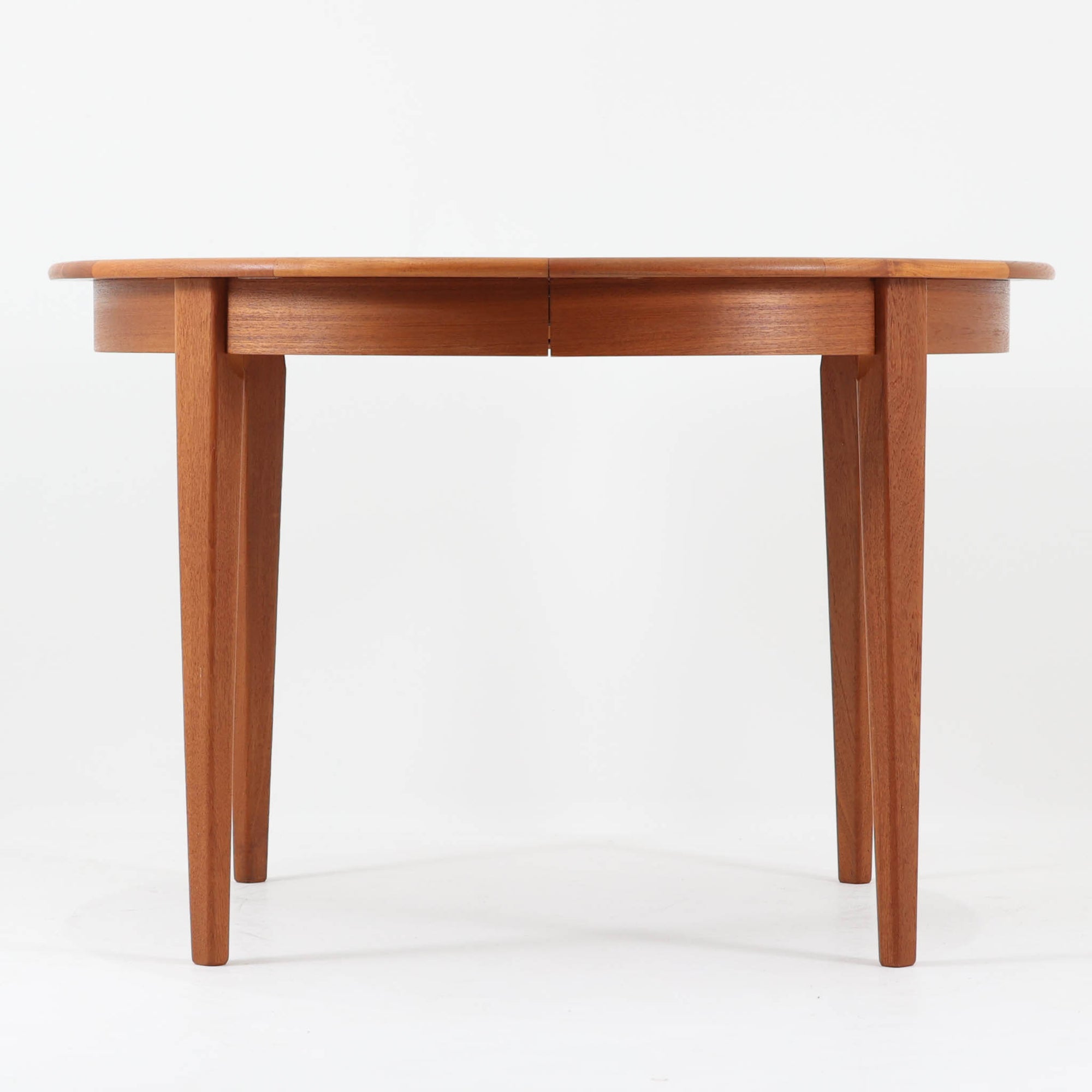 デンマーク製の北欧ビンテージ円形ダイニングテーブルです。チーク材の美しい木目が天板いっぱいに広がり、縁に施されたなだらかな丸みがやわらかな印象を与えます。幅110cmから165cm、さらに220cmまで拡張可能なエクステンション構造で、来客時にもゆとりあるレイアウトを実現。幕板から脚部へとつながる端正なフォルムは職人の確かな技術を感じさせます。家族の団らんからホームパーティーまで幅広く活躍し、経年により深みを増した色艶が空間に温もりと存在感をもたらす一台です。