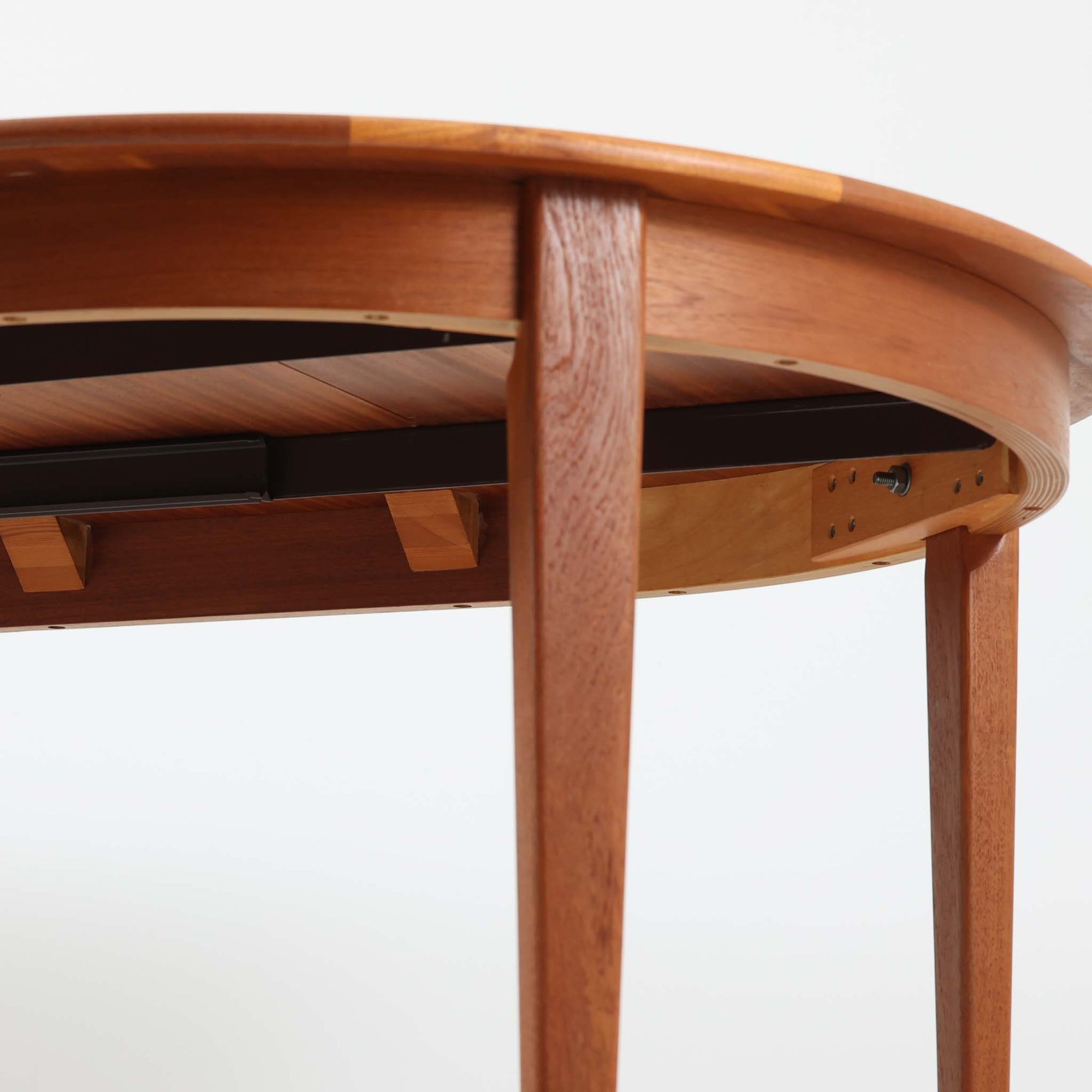 デンマーク製の北欧ビンテージ円形ダイニングテーブルです。チーク材の美しい木目が天板いっぱいに広がり、縁に施されたなだらかな丸みがやわらかな印象を与えます。幅110cmから165cm、さらに220cmまで拡張可能なエクステンション構造で、来客時にもゆとりあるレイアウトを実現。幕板から脚部へとつながる端正なフォルムは職人の確かな技術を感じさせます。家族の団らんからホームパーティーまで幅広く活躍し、経年により深みを増した色艶が空間に温もりと存在感をもたらす一台です。