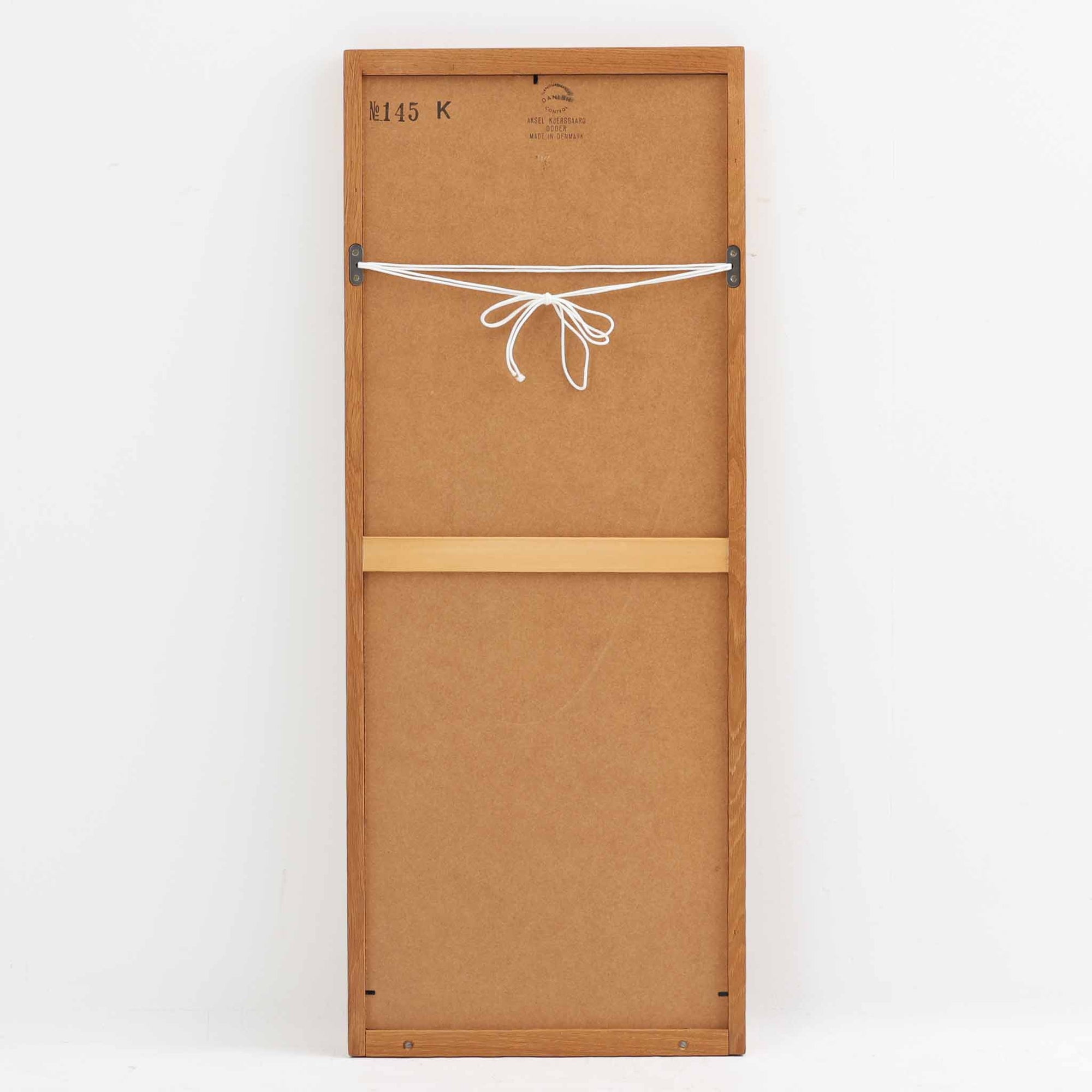 デンマークのデザイナー、Kai Kristiansen（カイ・クリスチャンセン）がAksel Kjersgaard（アクセル・キアスゴー）社のために手がけた立て掛けミラー「No.145」です。オーク材の美しい木目を活かしたフレームは細部まで丁寧に仕上げられ、角の木栓や滑らかな面取りなど北欧家具らしい繊細な職人技が光ります。高さ104cmと程よいサイズ感で、玄関や寝室、リビングなど幅広い空間に馴染みます。背面には壁掛け用の紐が付属していますが、重量があるため立て掛けでの使用をおすすめします。経年により深みを増したオークの質感が空間に温かみを添えるビンテージアイテムです。