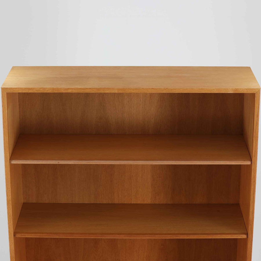 Hans J. Wegner（ハンス・J・ウェグナー）によるデザインで、Ry Mobler社から発表されたブックシェルフ「RY8」です。オーク材を用いたナチュラルな風合いと端正なラインが美しく、ウェグナーらしい機能美を感じさせます。通常モデルでは1枚が固定棚で他は可動棚となっていますが、本品は全ての棚板が取り外し可能な希少タイプで、用途に応じて高さを自在に調整できます。背面には製造年月のスタンプが残り、当時のクラフトマンシップを今に伝えています。書籍収納はもちろん、リビングやオフィスのディスプレイシェルフとしても活躍する一台です。