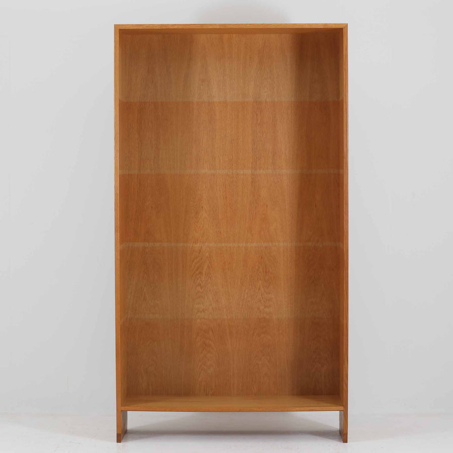 Hans J. Wegner（ハンス・J・ウェグナー）によるデザインで、Ry Mobler社から発表されたブックシェルフ「RY8」です。オーク材を用いたナチュラルな風合いと端正なラインが美しく、ウェグナーらしい機能美を感じさせます。通常モデルでは1枚が固定棚で他は可動棚となっていますが、本品は全ての棚板が取り外し可能な希少タイプで、用途に応じて高さを自在に調整できます。背面には製造年月のスタンプが残り、当時のクラフトマンシップを今に伝えています。書籍収納はもちろん、リビングやオフィスのディスプレイシェルフとしても活躍する一台です。