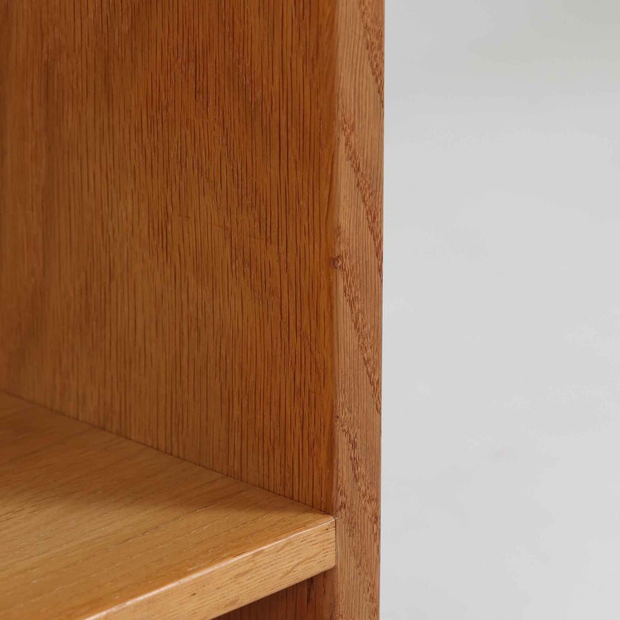 Hans J. Wegner（ハンス・J・ウェグナー）によるデザインで、Ry Mobler社から発表されたブックシェルフ「RY8」です。オーク材を用いたナチュラルな風合いと端正なラインが美しく、ウェグナーらしい機能美を感じさせます。通常モデルでは1枚が固定棚で他は可動棚となっていますが、本品は全ての棚板が取り外し可能な希少タイプで、用途に応じて高さを自在に調整できます。背面には製造年月のスタンプが残り、当時のクラフトマンシップを今に伝えています。書籍収納はもちろん、リビングやオフィスのディスプレイシェルフとしても活躍する一台です。
