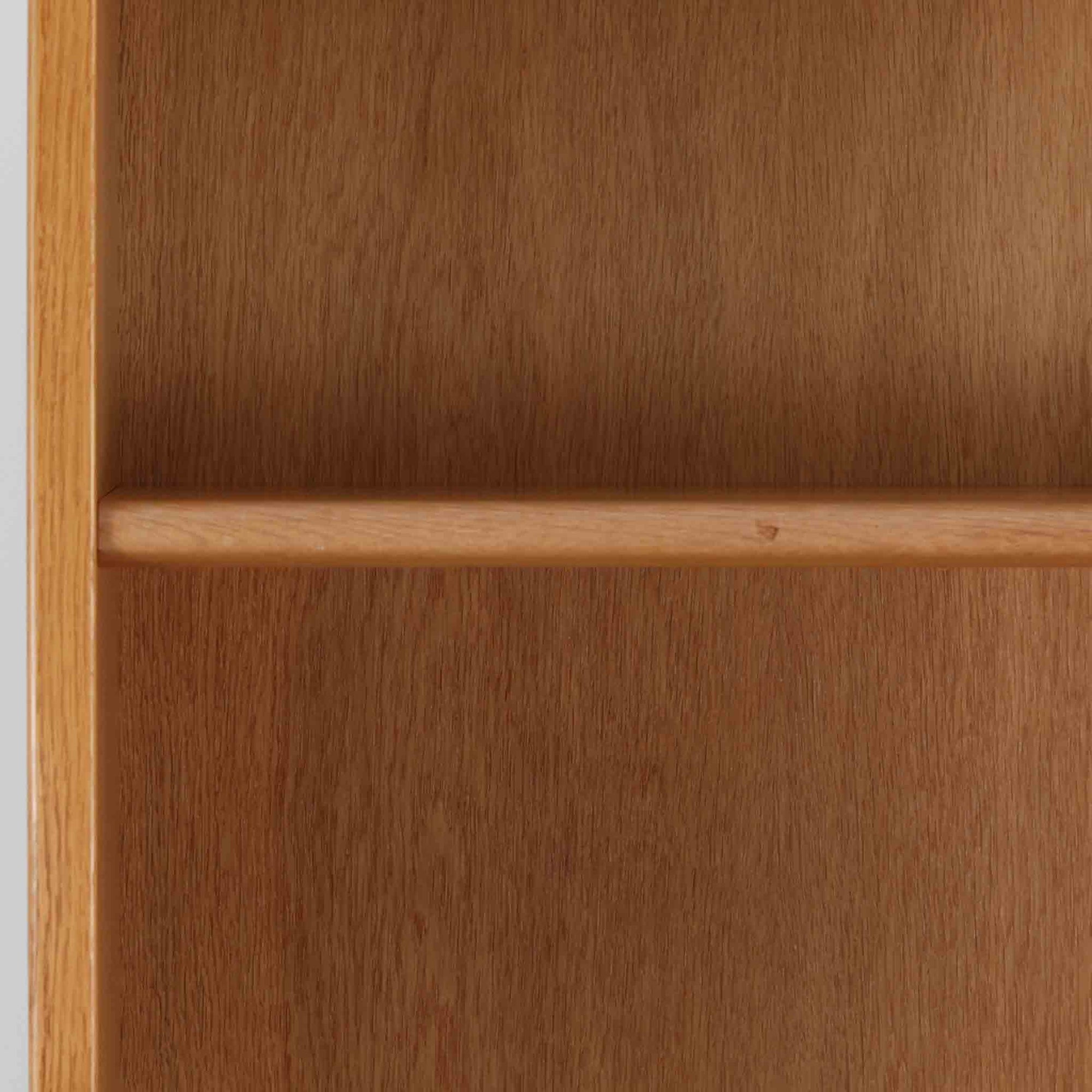 Hans J. Wegner（ハンス・J・ウェグナー）によるデザインで、Ry Mobler社から発表されたブックシェルフ「RY8」です。オーク材を用いたナチュラルな風合いと端正なラインが美しく、ウェグナーらしい機能美を感じさせます。通常モデルでは1枚が固定棚で他は可動棚となっていますが、本品は全ての棚板が取り外し可能な希少タイプで、用途に応じて高さを自在に調整できます。背面には製造年月のスタンプが残り、当時のクラフトマンシップを今に伝えています。書籍収納はもちろん、リビングやオフィスのディスプレイシェルフとしても活躍する一台です。