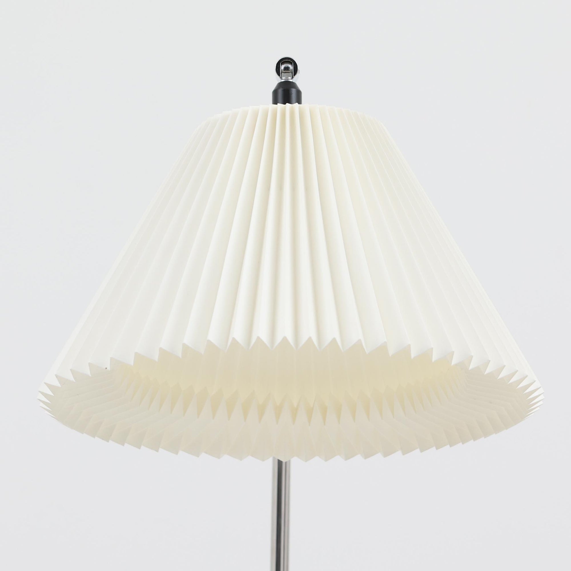 Michael Bang（マイケル・バン）によるデザインで、Le Klint（レ・クリント）から発表されたフロアランプModel 321です。高さ131cmのスチール製フレームは、無駄のない直線的なフォルムと精巧なディテールが際立ち、モダンな空間に調和します。特徴的なスライド機構によりランプの高さを調整でき、読書灯から間接照明まで幅広い用途に対応。ハンドクラフトによるプリーツシェードは柔らかい光を生み出し、北欧ビンテージならではの温もりと機能美を感じさせます。