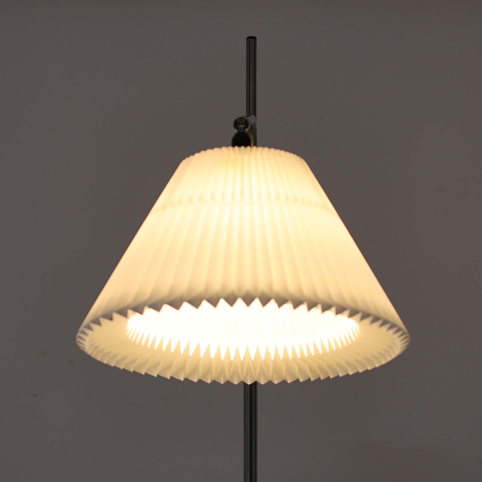 Michael Bang（マイケル・バン）によるデザインで、Le Klint（レ・クリント）から発表されたフロアランプModel 321です。高さ131cmのスチール製フレームは、無駄のない直線的なフォルムと精巧なディテールが際立ち、モダンな空間に調和します。特徴的なスライド機構によりランプの高さを調整でき、読書灯から間接照明まで幅広い用途に対応。ハンドクラフトによるプリーツシェードは柔らかい光を生み出し、北欧ビンテージならではの温もりと機能美を感じさせます。