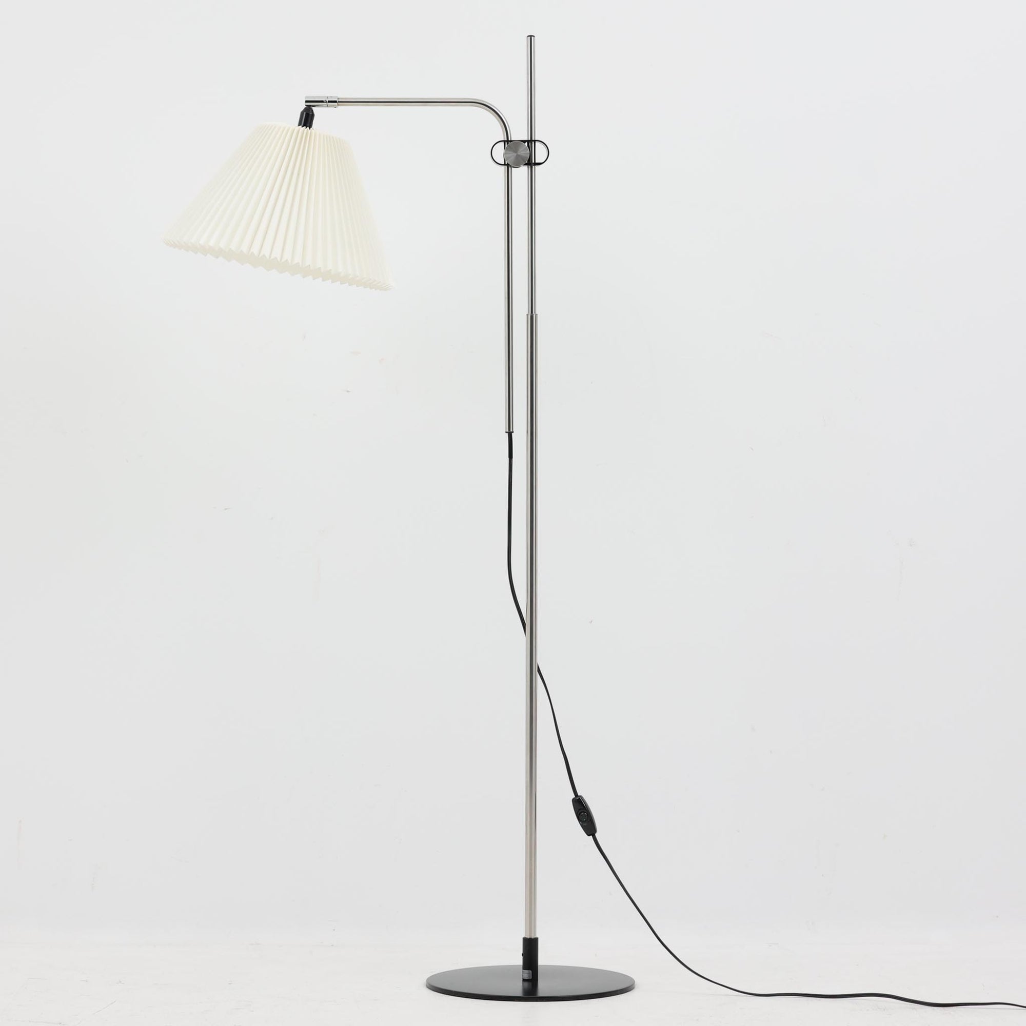 Michael Bang（マイケル・バン）によるデザインで、Le Klint（レ・クリント）から発表されたフロアランプModel 321です。高さ131cmのスチール製フレームは、無駄のない直線的なフォルムと精巧なディテールが際立ち、モダンな空間に調和します。特徴的なスライド機構によりランプの高さを調整でき、読書灯から間接照明まで幅広い用途に対応。ハンドクラフトによるプリーツシェードは柔らかい光を生み出し、北欧ビンテージならではの温もりと機能美を感じさせます。