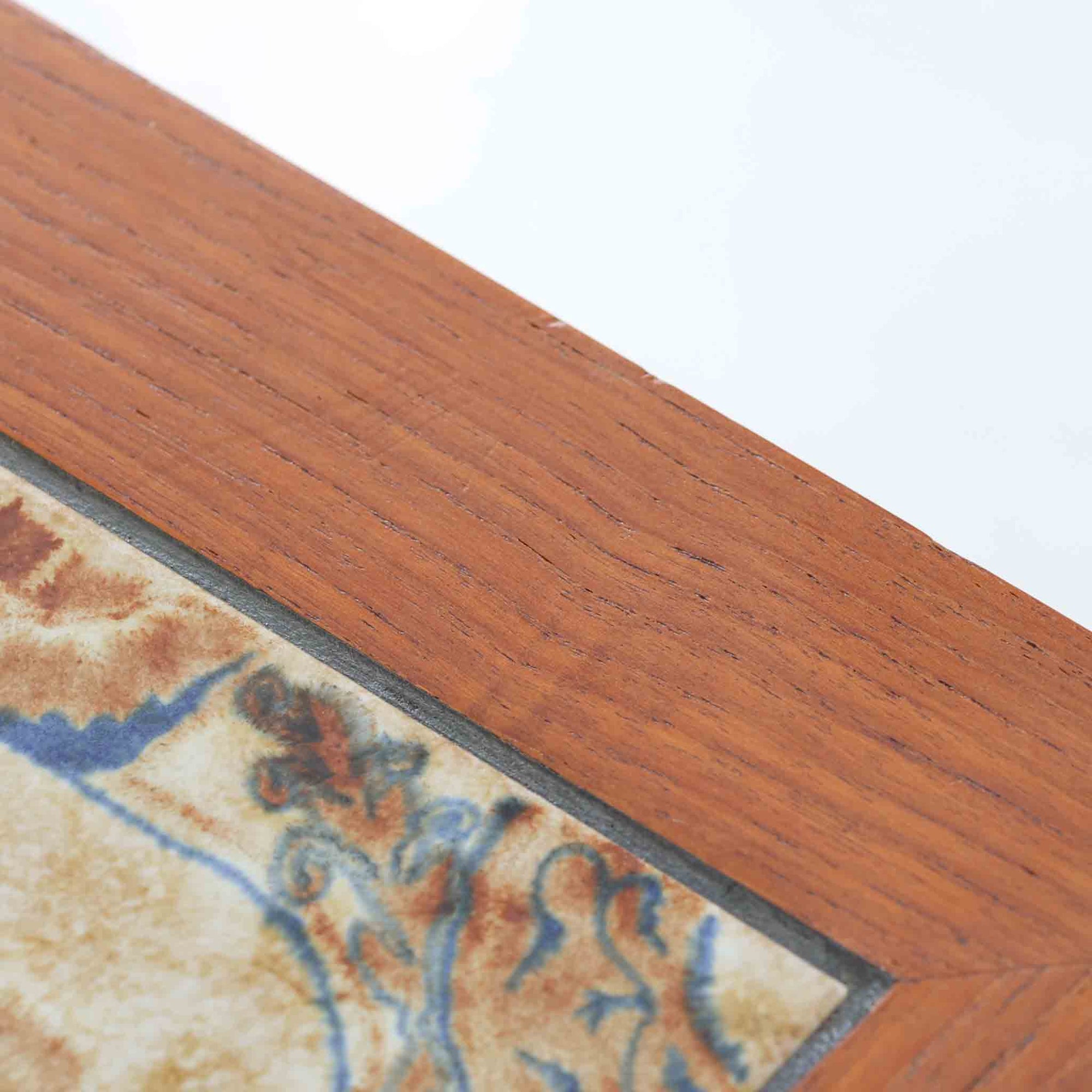 チーク材のフレームに陶磁器タイルを組み合わせたサイドテーブルは、温かみのある木肌と絵柄タイルの表情が調和した北欧ビンテージらしい一品です。天板中央に配されたタイルは、実用性に優れつつ装飾性も高く、経年による釉薬の風合いが落ち着いた存在感を演出します。直線的で端正な脚部構造は安定感があり、ソファ脇の補助台やディスプレイ台、花器やランプを置く台としても取り入れやすく、暮らしの中で静かなアクセントとなるビンテージ家具です。