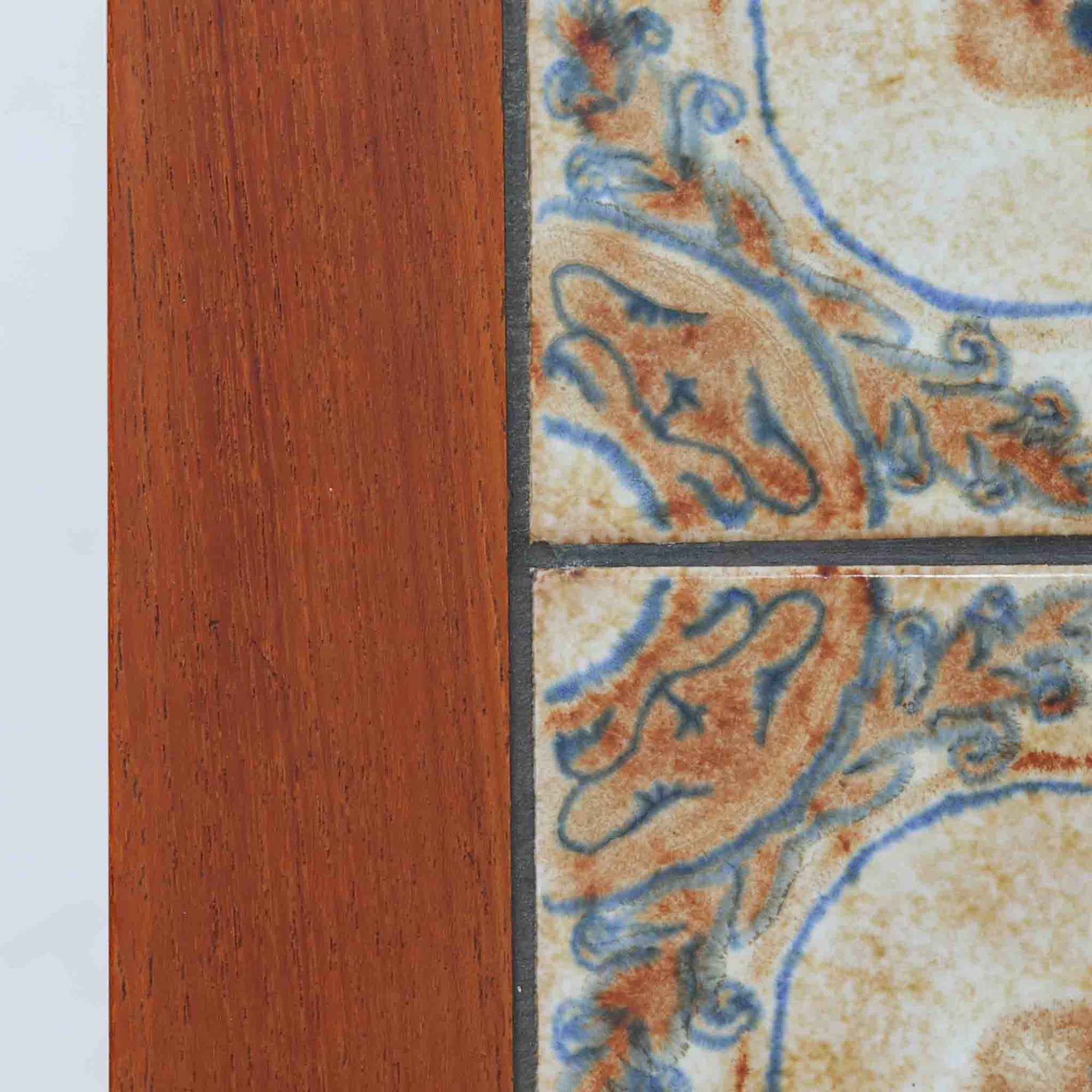 チーク材のフレームに陶磁器タイルを組み合わせたサイドテーブルは、温かみのある木肌と絵柄タイルの表情が調和した北欧ビンテージらしい一品です。天板中央に配されたタイルは、実用性に優れつつ装飾性も高く、経年による釉薬の風合いが落ち着いた存在感を演出します。直線的で端正な脚部構造は安定感があり、ソファ脇の補助台やディスプレイ台、花器やランプを置く台としても取り入れやすく、暮らしの中で静かなアクセントとなるビンテージ家具です。