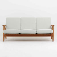 Hans J. Wegner（ハンス・J・ウェグナー）がデザインし、Getama社から発表されたGE240トリプルソファです。通称「Cigar Sofa」とも呼ばれる名作で、丸みを帯びたアームと堅牢なオーク材フレームが特徴です。背面まで美しい格子状のデザインは空間に軽やかさを与え、どの角度から見ても存在感があります。ライトグレー系の張地はアクリルとウールをブレンドした素材で、柔らかな風合いと高い耐久性を備えています。北欧家具らしいシンプルさと快適さを兼ね備え、リビングを上質に彩るビンテージソファです。