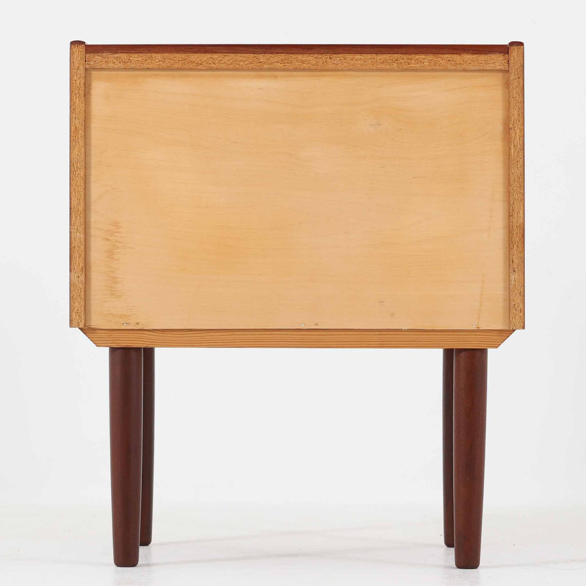 チーク材の豊かな木目が美しいこちらのサイドチェストは、北欧ビンテージらしい端正なデザインと実用性を兼ね備えた一台です。天板の縁には立ち上がりが施され、小物の転落を防ぐ工夫がされています。引き出し下のオープンスペースは本や雑貨の収納に便利で、ソファやベッドサイドに置けばサイドテーブルとしても活躍します。丸みを帯びた持ち手やテーパードレッグが柔らかな印象を与え、経年変化による木肌の深みが空間に温もりを添える逸品です。