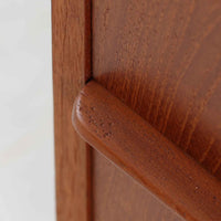 デンマーク製の8段チェストで、上質なチーク材の木目が存在感を放つ北欧ビンテージらしい一品です。細身の脚部に支えられた軽やかな佇まいと、北欧家具らしいバータイプの取っ手が、すっきりとした印象を与えます。衣類や小物をたっぷり収納でき、寝室やリビングで圧迫感なく使える点も魅力です。経年により深みを増した色艶が空間を温かく彩り、実用性と美しさを兼ね備えたチェストで、デンマークでも8段タイプは流通が少なく希少なモデルです。