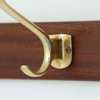 チーク材の温もりと真鍮色の金具が美しく調和したこちらのハンガーラックは、北欧ビンテージらしい上品な存在感を放つ壁掛けタイプの一品です。6つのフックが備わっており、玄関先や廊下でのコートや帽子、バッグの収納に最適。経年により味わいを増した木部の質感と、マットな金属パーツの組み合わせが空間に程よいアクセントを加えてくれます。実用性と装飾性を兼ね備えた、希少なビンテージアイテムです。