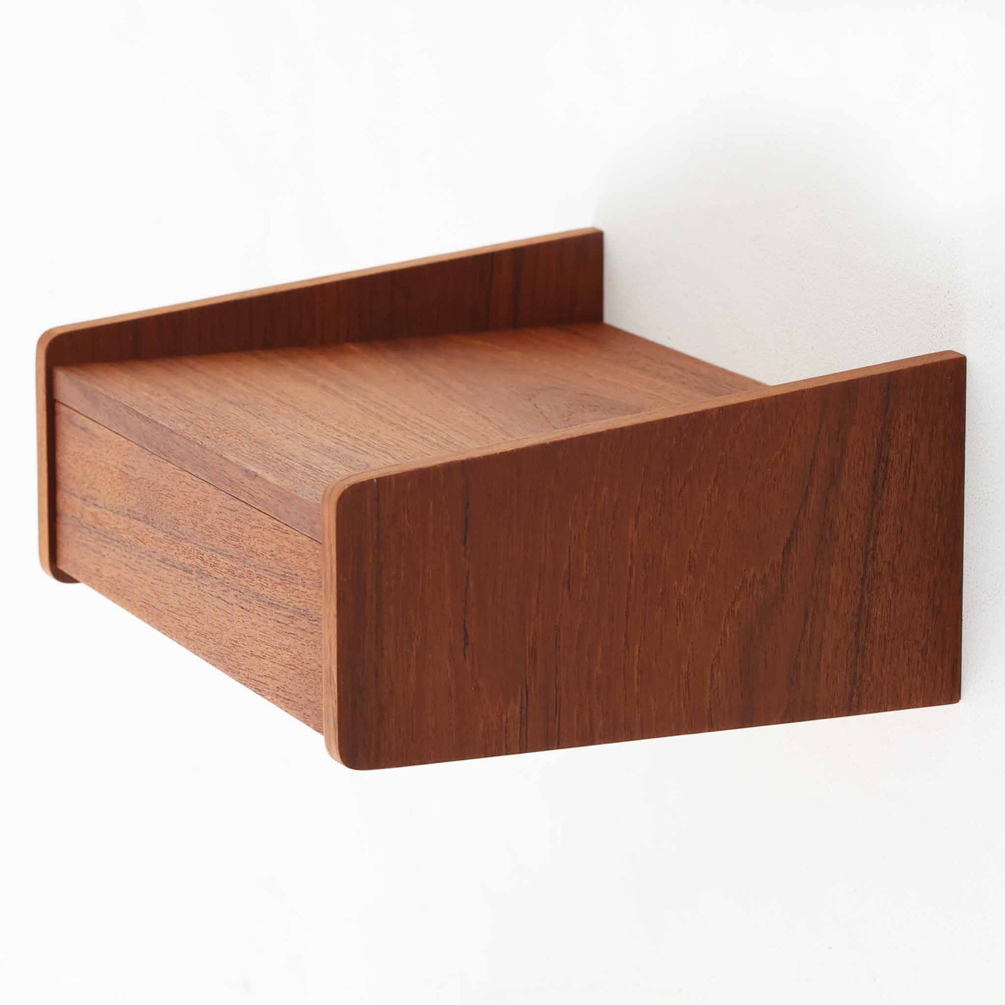 チーク材を使用したこちらのウォールシェルフは、立ち上がりの付いたサイドパネルが滑らかな曲線を描く、美しいシルエットが魅力の北欧ビンテージ家具です。壁面に取り付けることで省スペースながらも収納力を確保でき、ベッドサイドや玄関、リビングのアクセントとして活躍します。背面構造からビスでの取り付け仕様となっており、取り付け跡や構造の素朴さからも当時の職人仕事の温もりが感じられます。小ぶりながらも素材の魅力と機能性を備えた一品です。