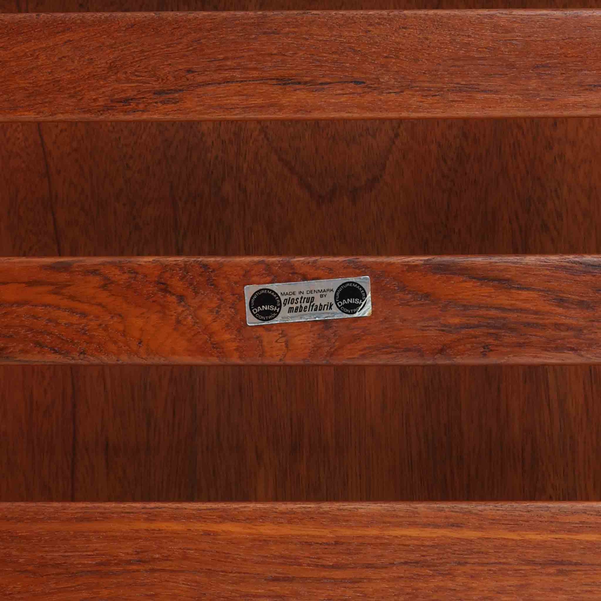 Grete Jalkがデザインし、Glostrup Mobelfabrikで製作されたこちらのセンターテーブルは、端正なプロポーションと軽やかな構造が魅力の北欧ビンテージ品です。幅160cmのゆとりある天板下にはスラット状の棚板を備え、雑誌やブランケットなどを整理しながら使える実用性も兼ね備えています。丸みを帯びた脚部や天板縁の丁寧な仕上げからは、女性デザイナーらしい繊細な美意識と当時の高い木工技術が感じられ、経年により深みを増した木肌が空間に落ち着いた存在感をもたらします。