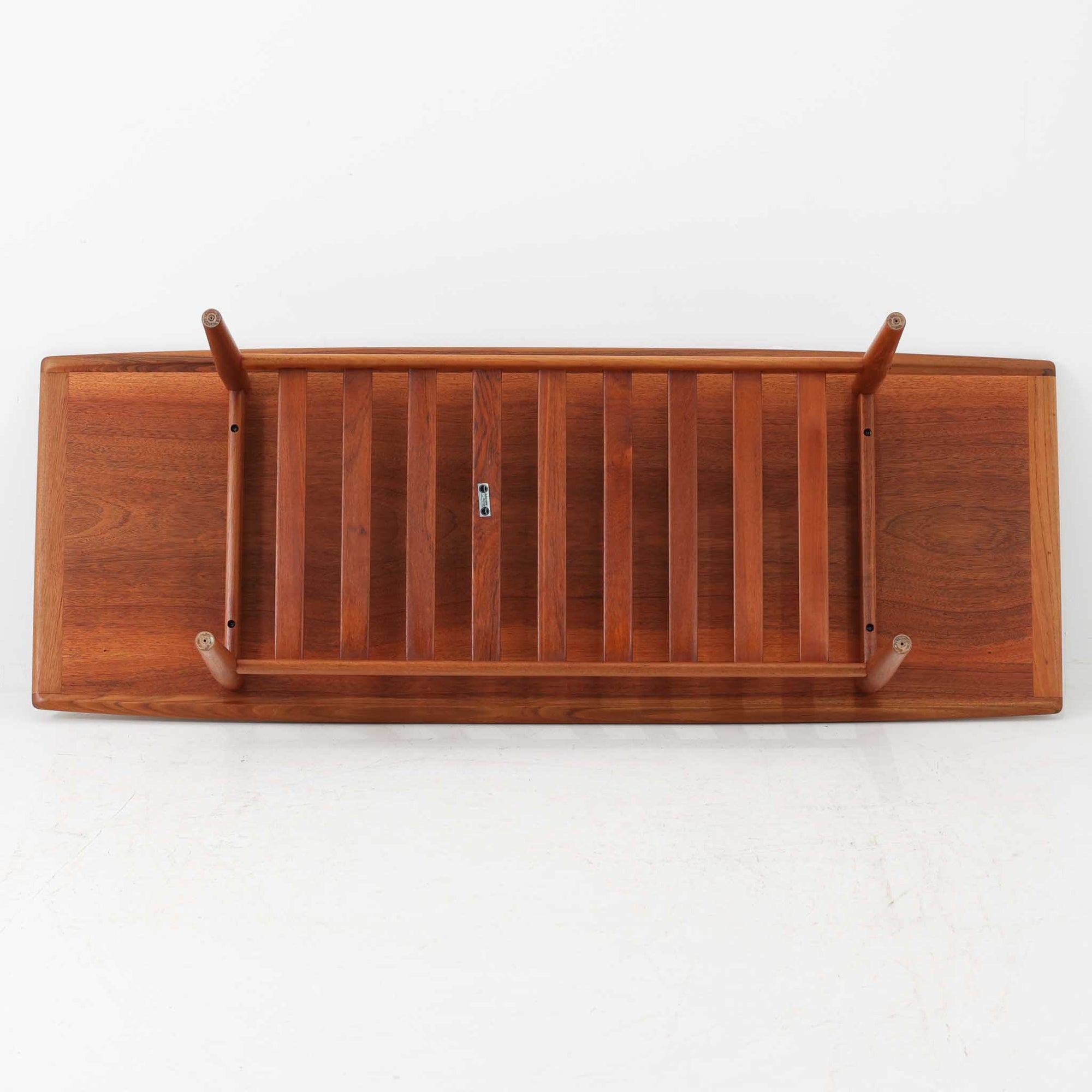 Grete Jalkがデザインし、Glostrup Mobelfabrikで製作されたこちらのセンターテーブルは、端正なプロポーションと軽やかな構造が魅力の北欧ビンテージ品です。幅160cmのゆとりある天板下にはスラット状の棚板を備え、雑誌やブランケットなどを整理しながら使える実用性も兼ね備えています。丸みを帯びた脚部や天板縁の丁寧な仕上げからは、女性デザイナーらしい繊細な美意識と当時の高い木工技術が感じられ、経年により深みを増した木肌が空間に落ち着いた存在感をもたらします。