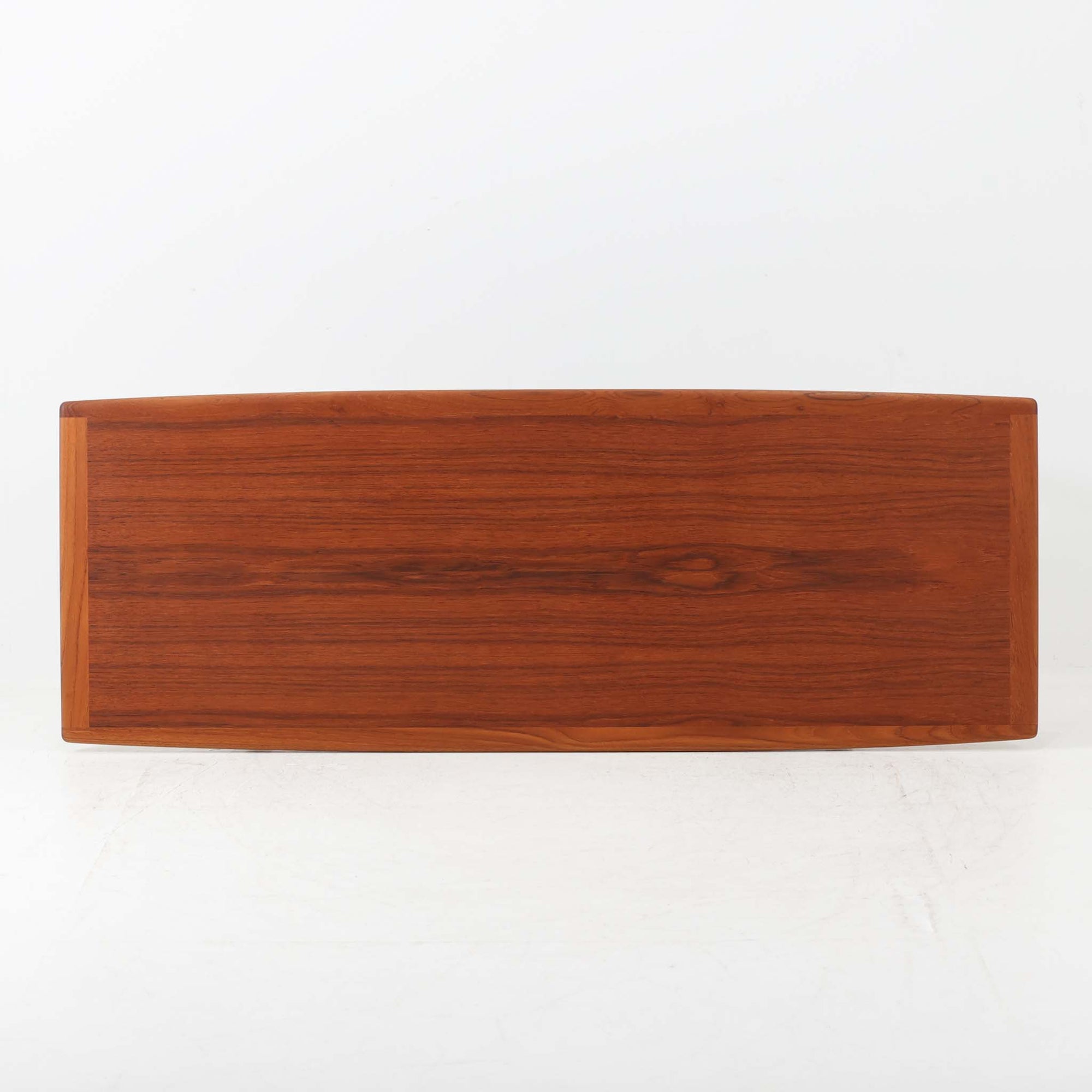 Grete Jalkがデザインし、Glostrup Mobelfabrikで製作されたこちらのセンターテーブルは、端正なプロポーションと軽やかな構造が魅力の北欧ビンテージ品です。幅160cmのゆとりある天板下にはスラット状の棚板を備え、雑誌やブランケットなどを整理しながら使える実用性も兼ね備えています。丸みを帯びた脚部や天板縁の丁寧な仕上げからは、女性デザイナーらしい繊細な美意識と当時の高い木工技術が感じられ、経年により深みを増した木肌が空間に落ち着いた存在感をもたらします。