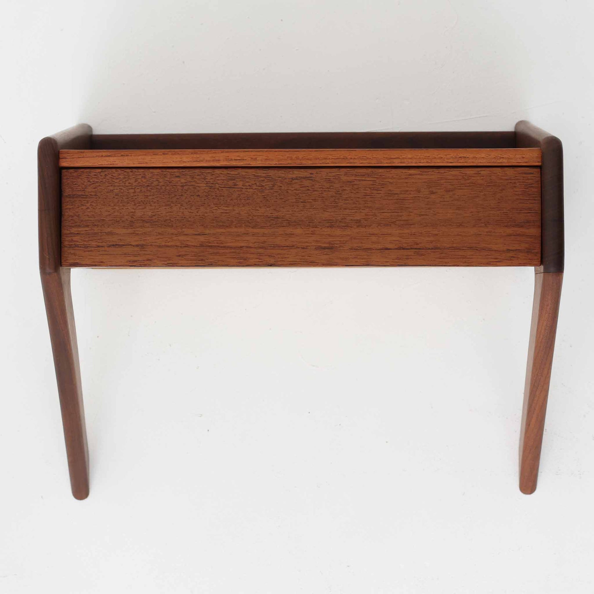 デンマーク製のチーク材ウォールシェルフで、シンプルながら洗練されたデザインが魅力の北欧ビンテージ家具です。壁付けタイプで引き出しを備えており、小物収納としても実用的です。前面や側面は柔らかな曲線を取り入れた造形で、温かみあるチーク材の質感と相まって上品な存在感を放ちます。寝室のベッドサイドや玄関の小物置きとしても活躍し、コンパクトながら空間を引き締めるアクセントになります。経年による風合いが味わいを深め、北欧家具らしい魅力を存分に感じられる一品です。