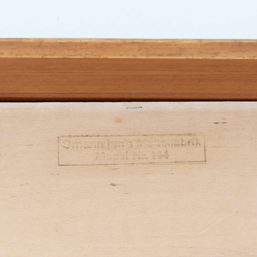 Gunni Omann（グンニ・オーマン）によるデザインで、Omann Jun社から発表されたModel 144ウォールシェルフです。チーク材を使用した上質な仕上がりで、シンプルながらも端正なフォルムと美しい木目が際立ちます。引き出しを備えているため、小物収納にも便利で、ベッドサイドや玄関先など限られたスペースでも活躍します。前板に施された小さなラウンド型の取っ手がデザインのアクセントとなり、北欧家具らしい機能美を感じさせます。経年による風合いが増し、空間に温かみと深みを添えるビンテージの逸品です。