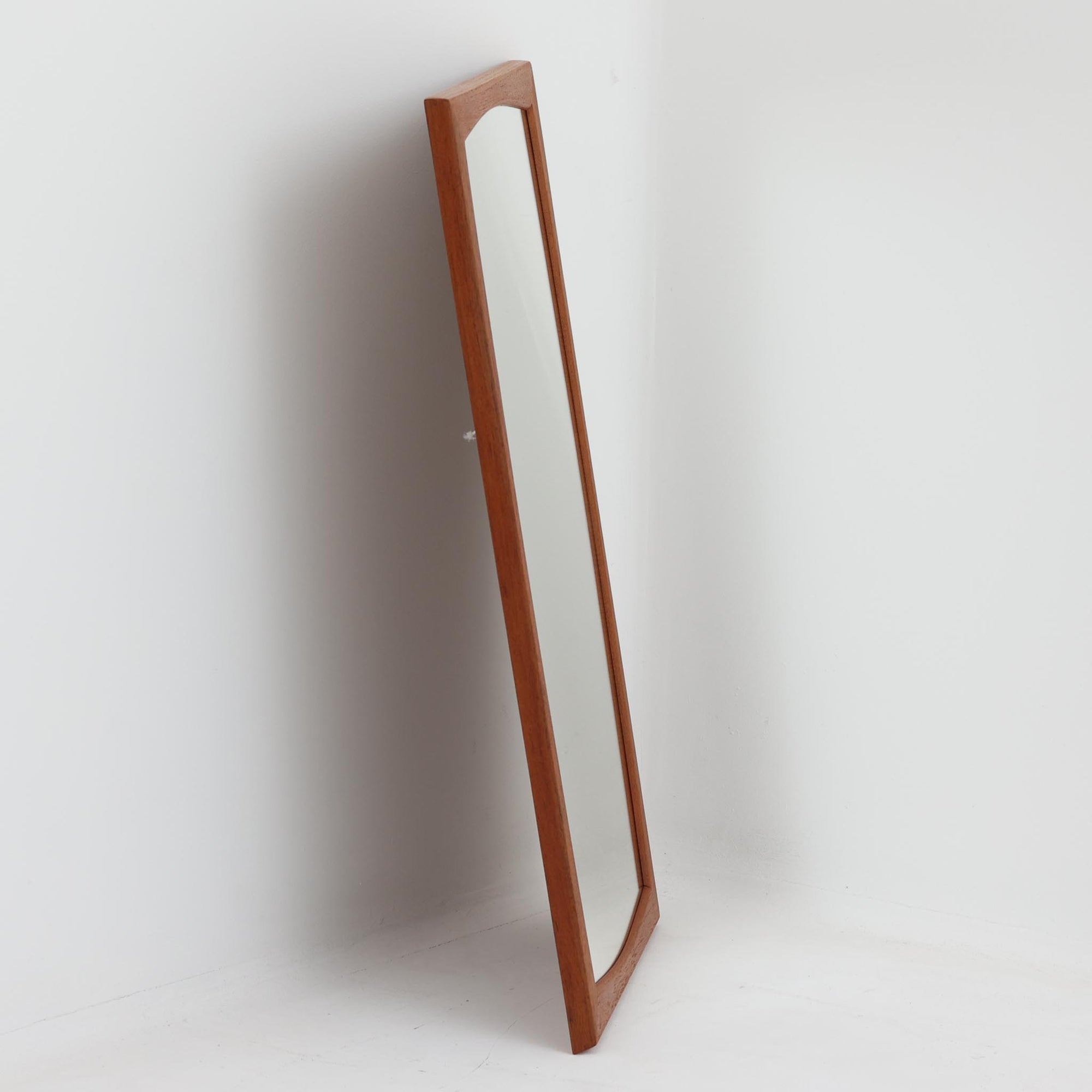 Kai Kristiansen（カイ・クリスチャンセン）がデザインし、Aksel Kjersgaard（アクセル・キアスゴー）社より製造されたNo.103の立て掛けミラーです。柔らかな曲線を描くチーク材のフレームは、丁寧な接合と美しい木目が際立ち、北欧デザインの洗練された職人技を感じさせます。無駄のないシルエットは空間を選ばず、壁掛けとしても立て掛けとしてもお使いいただけます。経年による深みのある色合いがチーク材の魅力を一層引き立て、玄関や寝室に上質な雰囲気を添える一品です。