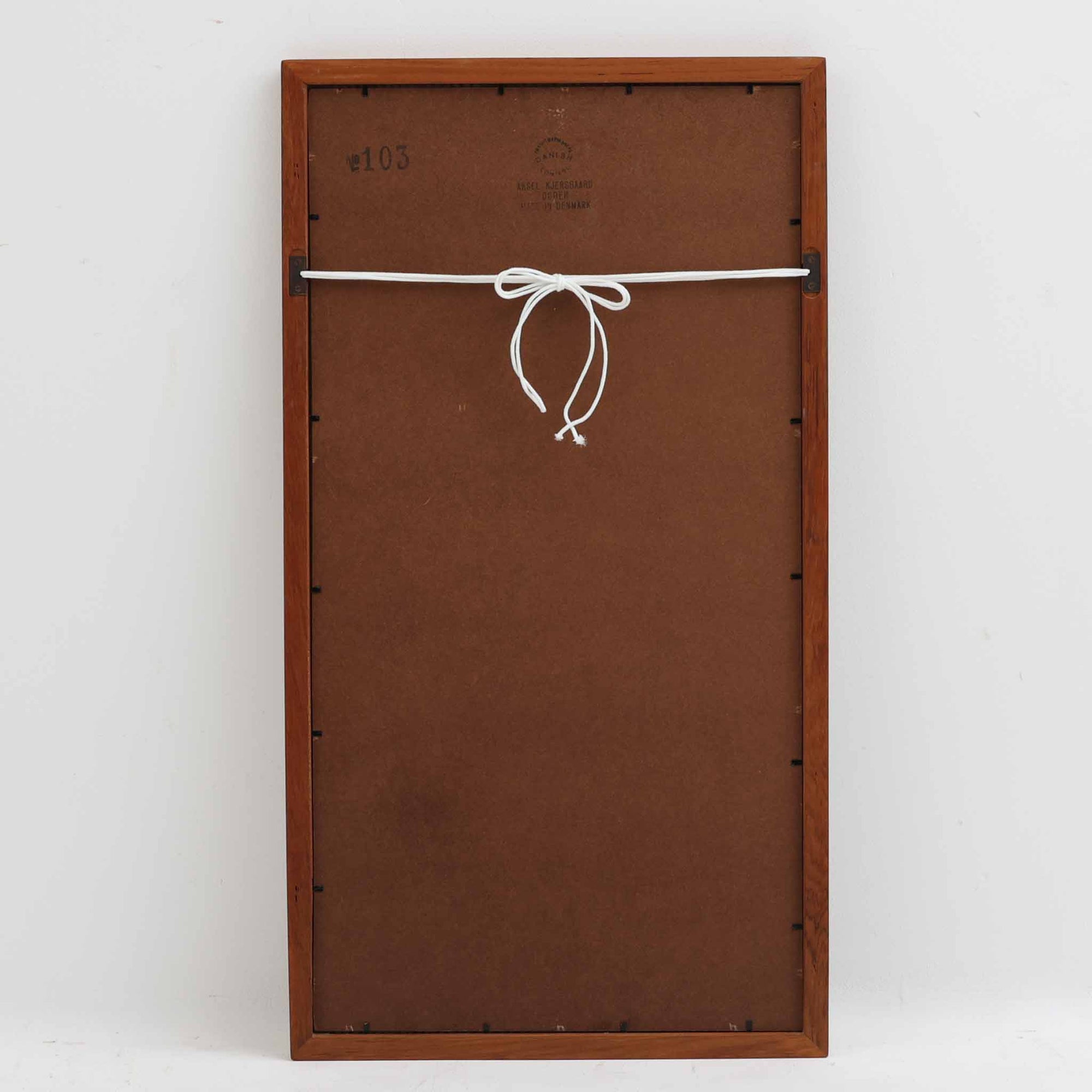 Kai Kristiansen（カイ・クリスチャンセン）がデザインし、Aksel Kjersgaard（アクセル・キアスゴー）社より製造されたNo.103の立て掛けミラーです。柔らかな曲線を描くチーク材のフレームは、丁寧な接合と美しい木目が際立ち、北欧デザインの洗練された職人技を感じさせます。無駄のないシルエットは空間を選ばず、壁掛けとしても立て掛けとしてもお使いいただけます。経年による深みのある色合いがチーク材の魅力を一層引き立て、玄関や寝室に上質な雰囲気を添える一品です。
