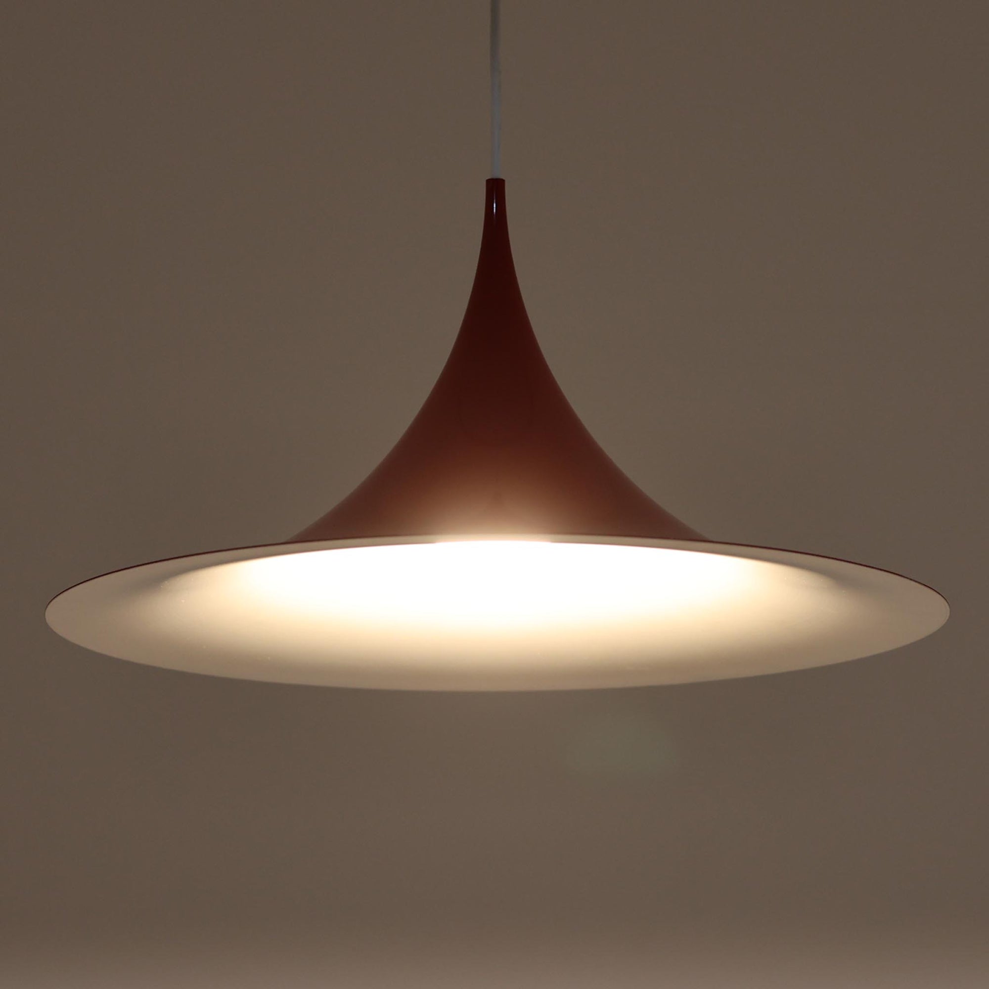 Claus Bonderup &amp; Torsten Thorupによってデザインされ、Fog &amp; Morup社から発表されたペンダントライト「Semi」です。直径47cmの存在感あるサイズと、シャープに絞り込まれた独特のフォルムが特徴です。鮮やかなレッドのカラーが空間にアクセントを与え、点灯時には下方向へ集中的に光を届けつつ、周囲をやわらかく照らします。1960年代に誕生したモダンデザインの象徴的な作品で、シンプルながらも彫刻的な美しさを備えています。北欧ビンテージならではの上質な佇まいで、ダイニングやリビングに華やかな雰囲気を添える一灯です。