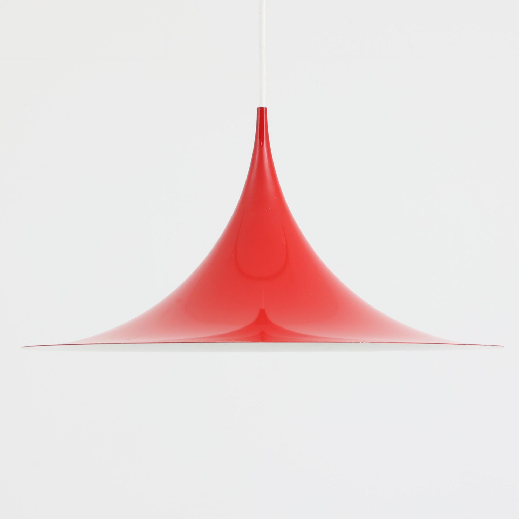 Claus Bonderup & Torsten Thorupによってデザインされ、Fog & Morup社から発表されたペンダントライト「Semi」です。直径47cmの存在感あるサイズと、シャープに絞り込まれた独特のフォルムが特徴です。鮮やかなレッドのカラーが空間にアクセントを与え、点灯時には下方向へ集中的に光を届けつつ、周囲をやわらかく照らします。1960年代に誕生したモダンデザインの象徴的な作品で、シンプルながらも彫刻的な美しさを備えています。北欧ビンテージならではの上質な佇まいで、ダイニングやリビングに華やかな雰囲気を添える一灯です。