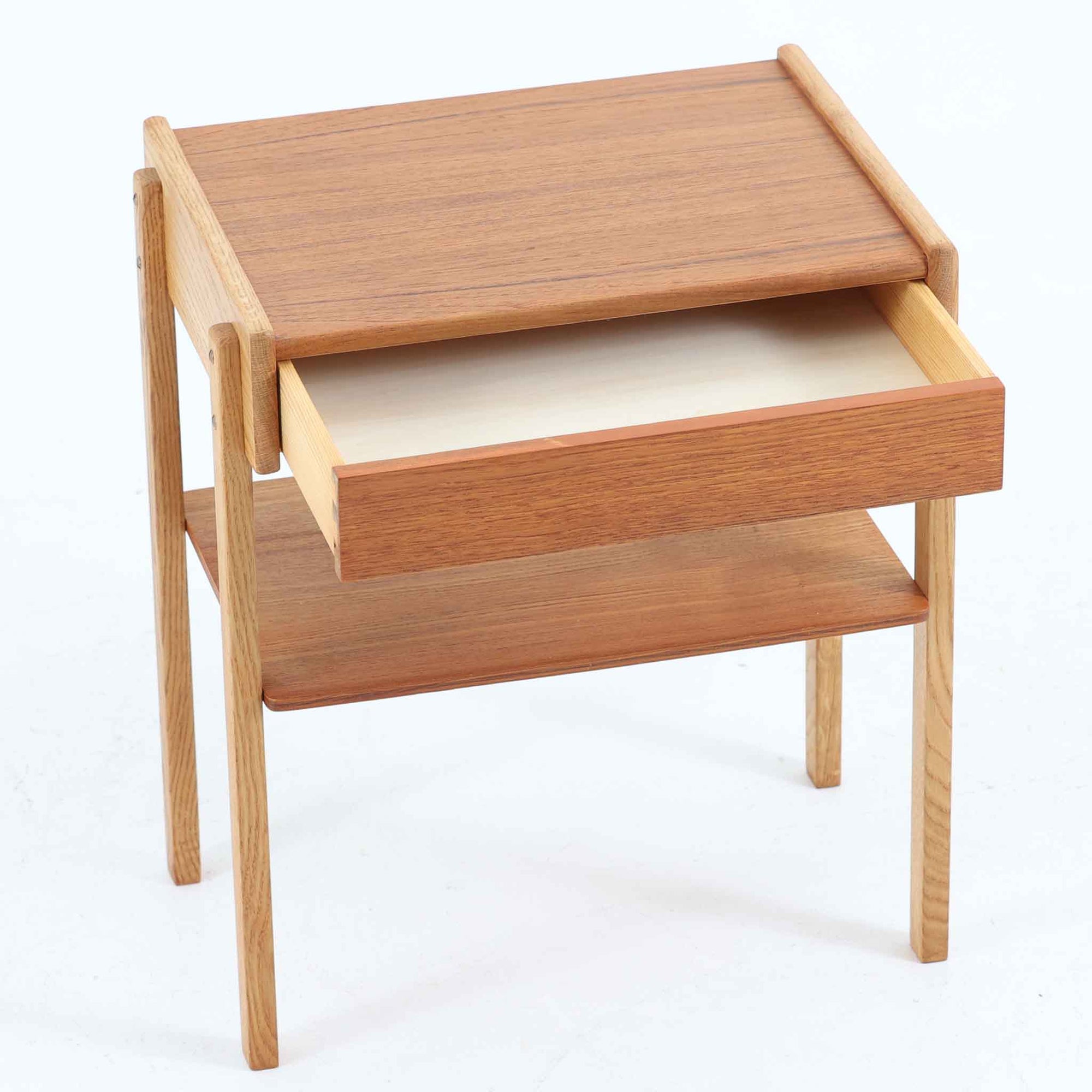 AB Carlstrom＆CO Mobelfabrik社製のサイドチェストは、チーク材とオーク材を組み合わせた北欧ビンテージ家具です。温かみのあるチークの引き出し前板と、明るいオークのフレームが美しいコントラストを生み出し、軽やかで洗練された印象を与えます。上段には小物収納に便利な引き出し、下段にはオープンシェルフを備え、実用性とデザイン性を両立。幅46cmとコンパクトなサイズ感は、ベッドサイドやソファ横でのサイドテーブルとしても最適で、限られたスペースにも収まりやすい設計です。シンプルながら素材の質感と北欧家具ならではの職人技が息づく一台で、空間に温もりと個性を添えてくれます。