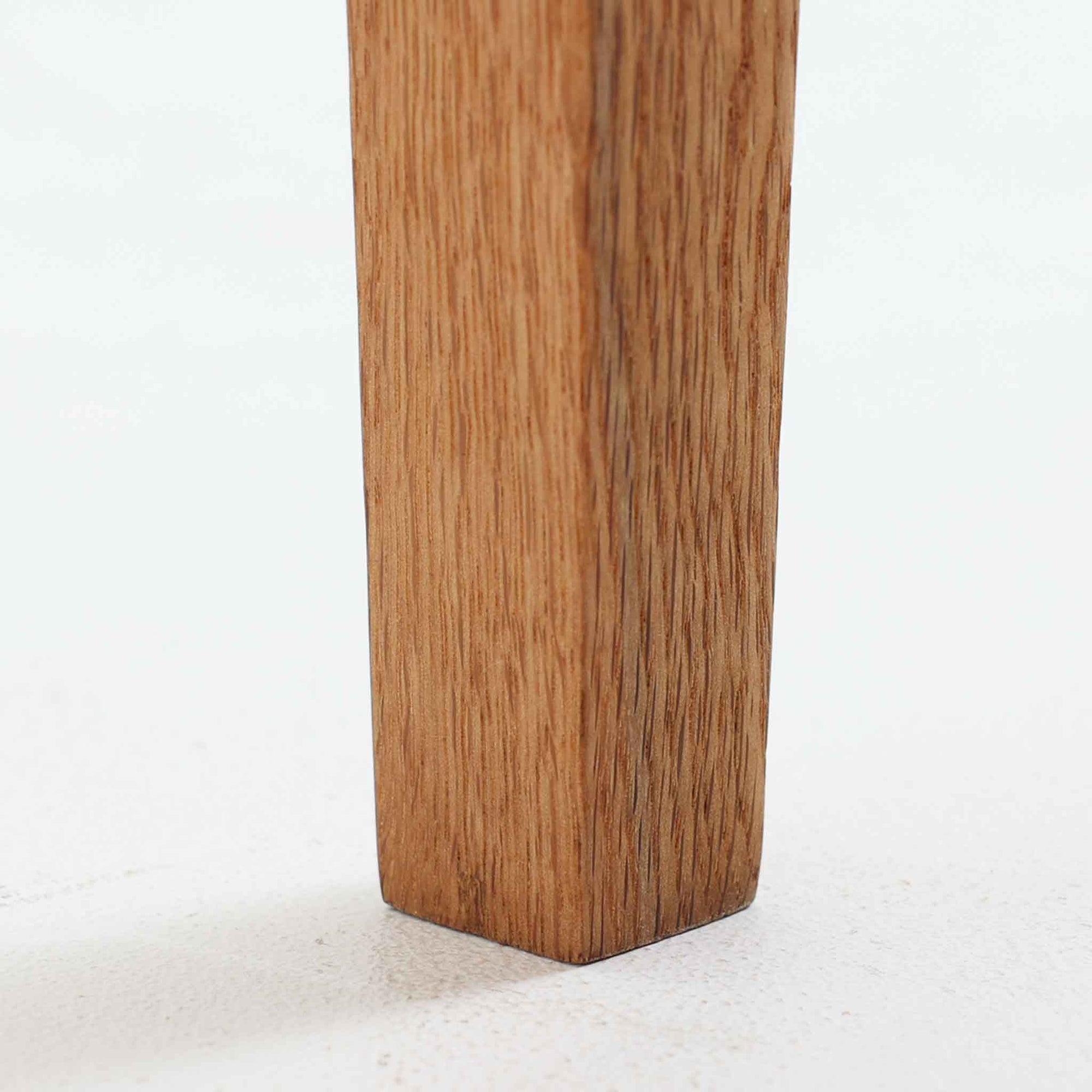 オーク材を用いたこちらの2段チェストは、北欧ビンテージ家具らしいシンプルかつ機能的なデザインが魅力です。直線的なフォルムに対し、細身でテーパーのかかった脚部が軽やかな印象を与え、空間を圧迫せずに置くことができます。幅60cmとコンパクトながら、2杯の引き出しは日用品や小物収納に便利で、ベッドサイドやリビングの補助収納としても最適です。経年により深みを増したオークの木肌が、温もりある雰囲気を演出する一点物です。