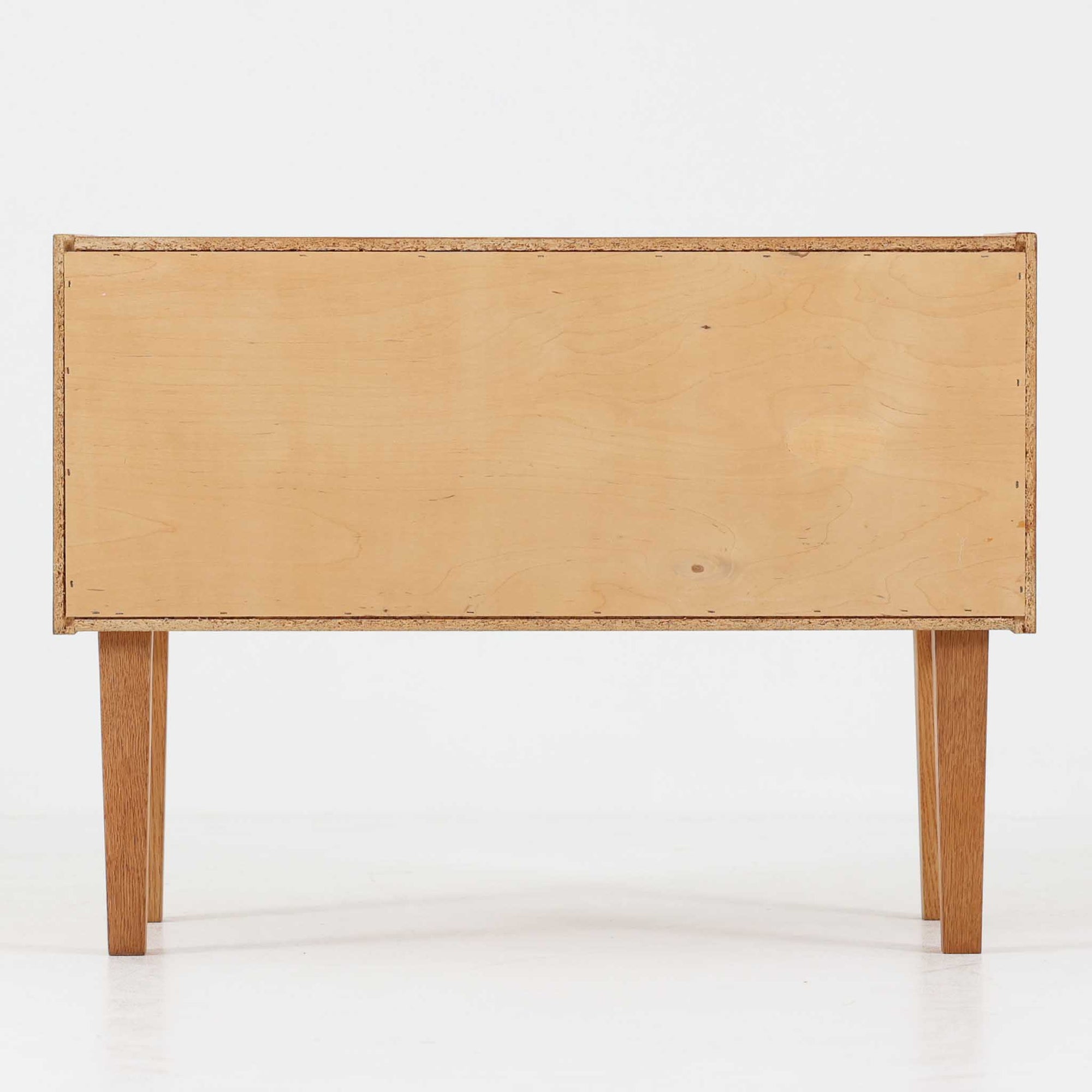 オーク材を用いたこちらの2段チェストは、北欧ビンテージ家具らしいシンプルかつ機能的なデザインが魅力です。直線的なフォルムに対し、細身でテーパーのかかった脚部が軽やかな印象を与え、空間を圧迫せずに置くことができます。幅60cmとコンパクトながら、2杯の引き出しは日用品や小物収納に便利で、ベッドサイドやリビングの補助収納としても最適です。経年により深みを増したオークの木肌が、温もりある雰囲気を演出する一点物です。