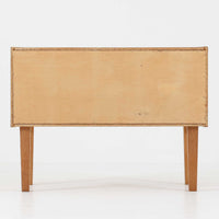 オーク材を用いたこちらの2段チェストは、北欧ビンテージ家具らしいシンプルかつ機能的なデザインが魅力です。直線的なフォルムに対し、細身でテーパーのかかった脚部が軽やかな印象を与え、空間を圧迫せずに置くことができます。幅60cmとコンパクトながら、2杯の引き出しは日用品や小物収納に便利で、ベッドサイドやリビングの補助収納としても最適です。経年により深みを増したオークの木肌が、温もりある雰囲気を演出する一点物です。