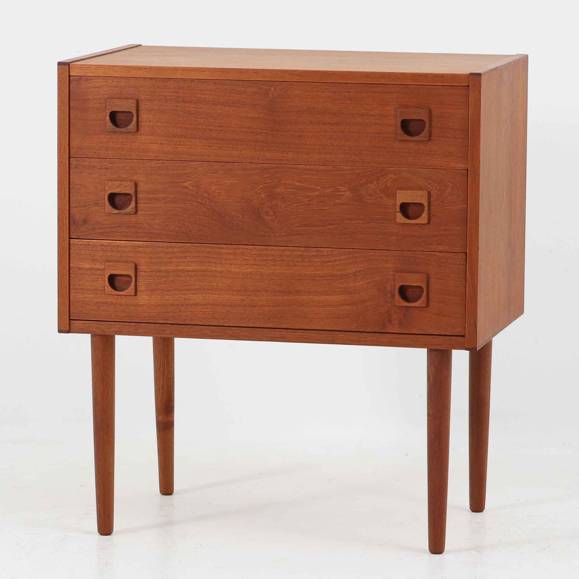 デンマーク製のチーク材を使用した3段チェストです。コンパクトな幅62cmのサイズ感ながら、3杯の引き出しを備え収納力に優れており、リビングや寝室、玄関先など幅広いシーンで活躍します。スクエア型の取っ手は彫り込みデザインで指掛かりが良く、シンプルながらも北欧家具らしい温もりと実用性を感じさせます。経年により深みを増したチーク材の色合いが、空間に落ち着きと上質な雰囲気をもたらし、ビンテージならではの魅力を楽しめる一台です。