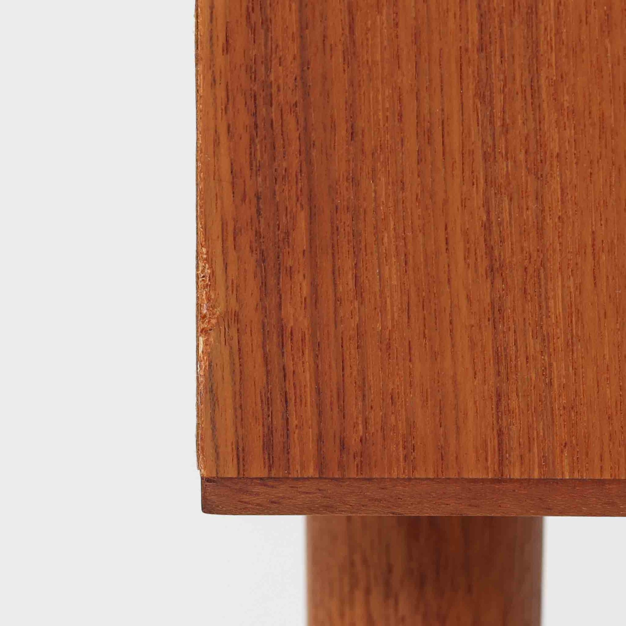 デンマーク製のチーク材を使用した3段チェストです。コンパクトな幅62cmのサイズ感ながら、3杯の引き出しを備え収納力に優れており、リビングや寝室、玄関先など幅広いシーンで活躍します。スクエア型の取っ手は彫り込みデザインで指掛かりが良く、シンプルながらも北欧家具らしい温もりと実用性を感じさせます。経年により深みを増したチーク材の色合いが、空間に落ち着きと上質な雰囲気をもたらし、ビンテージならではの魅力を楽しめる一台です。