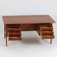 Omann Jun（オーマン・ユン）によるデザインで、同社から製造された両袖デスク「Model 75」です。チーク材の温かみある木目と、滑らかなエッジを描く天板ラインが美しく、北欧家具らしい上質な佇まいを感じさせます。左右に3段ずつ備えた引き出しは、実用性に優れながらも取手のデザインがアクセントとなっており、職人の細やかな技術が光ります。背面にも収納スペースが設けられており、空間の中央に置いても絵になる仕上がりです。ワークスペースや書斎に品格を添える、北欧ビンテージの名品デスクです。